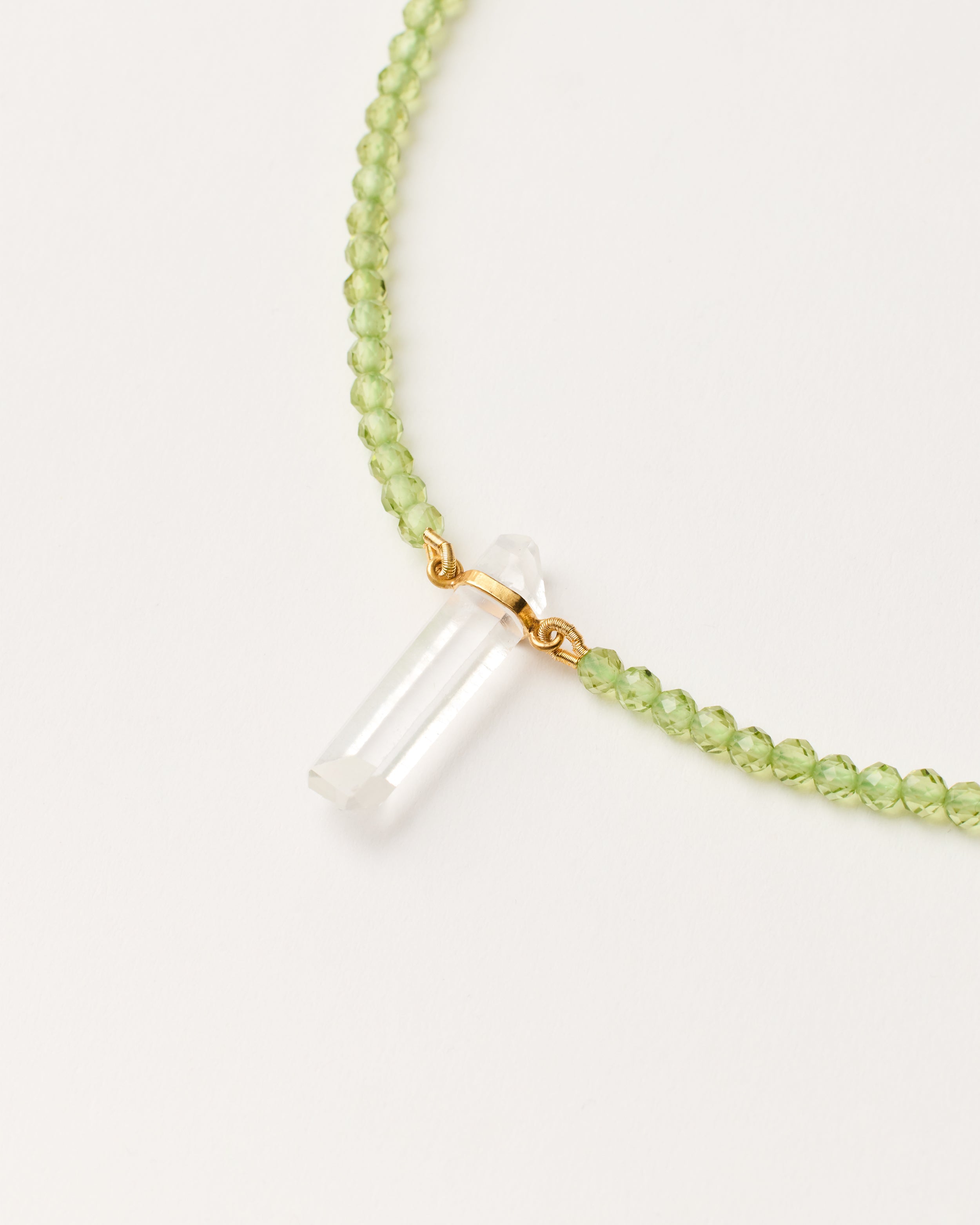 ENCARA OLMAR Peridot necklace with raw polished quartz point pendant, gold-plated silver 8 cm extension chain and clasp, arrowhead-shaped fantasy signature, and 4 mm faceted chrysolite bead strand.