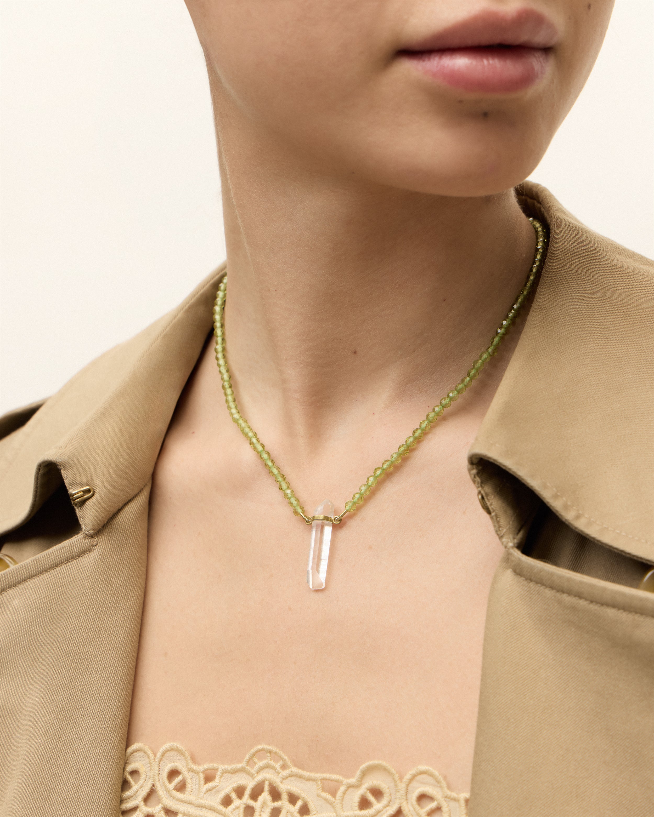 ENCARA OLMAR Peridot necklace with raw polished quartz point pendant, gold 8 cm extension chain and clasp, arrowhead-shaped fantasy signature, and 4 mm faceted chrysolite bead strand.