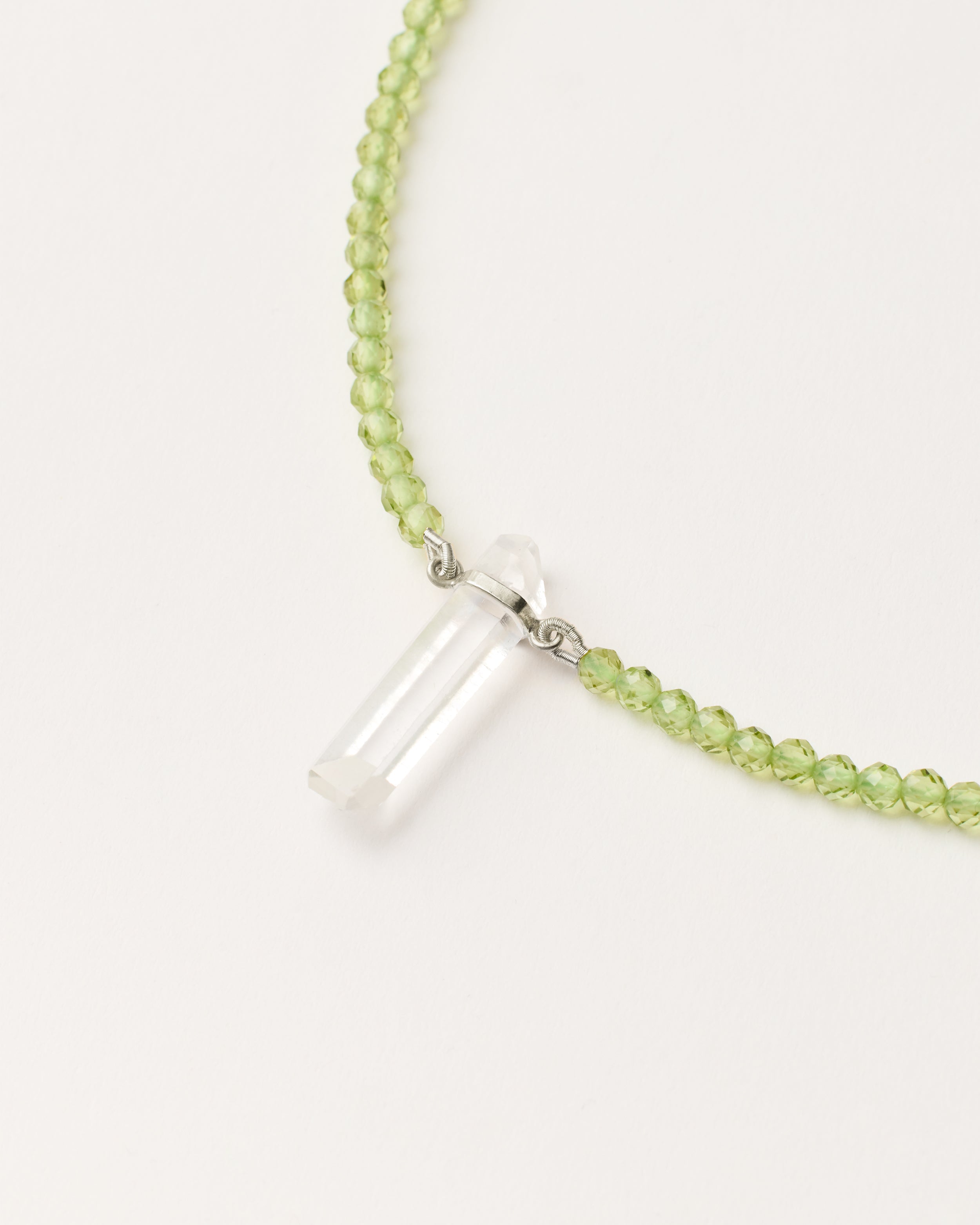 ENCARA OLMAR Peridot necklace with raw polished quartz point pendant, silver 8 cm extension chain and clasp, arrowhead-shaped fantasy signature, and 4 mm faceted chrysolite bead strand.