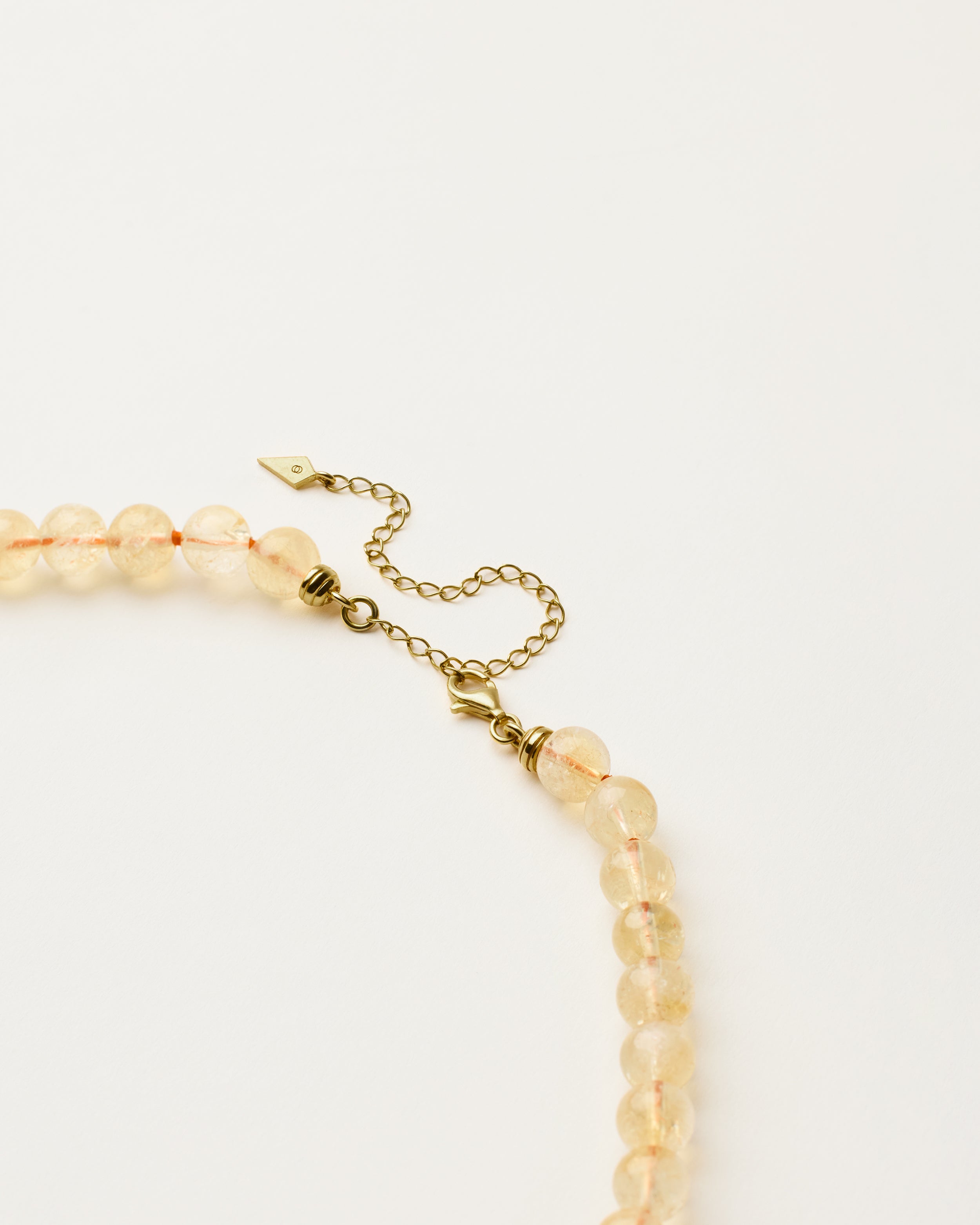 ENCARA SOLIS Citrine necklace with raw polished quartz point pendant, gold 8 cm extension chain and clasp, arrowhead-shaped fantasy signature, and 8 mm faceted citrine bead strand.