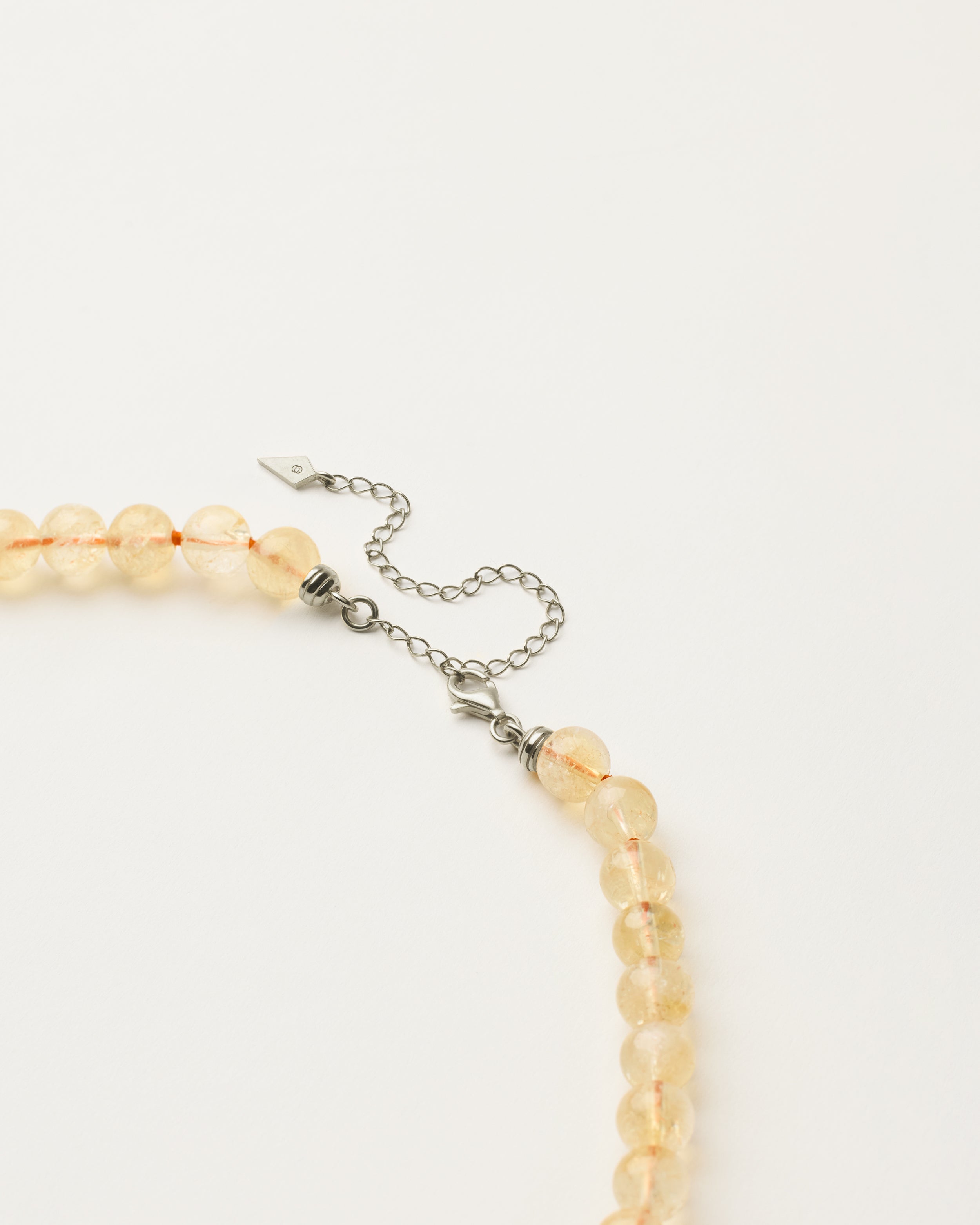 ENCARA SOLIS Citrine necklace with raw polished quartz point pendant, silver 8 cm extension chain and clasp, arrowhead-shaped fantasy signature, and 8 mm faceted citrine bead strand.