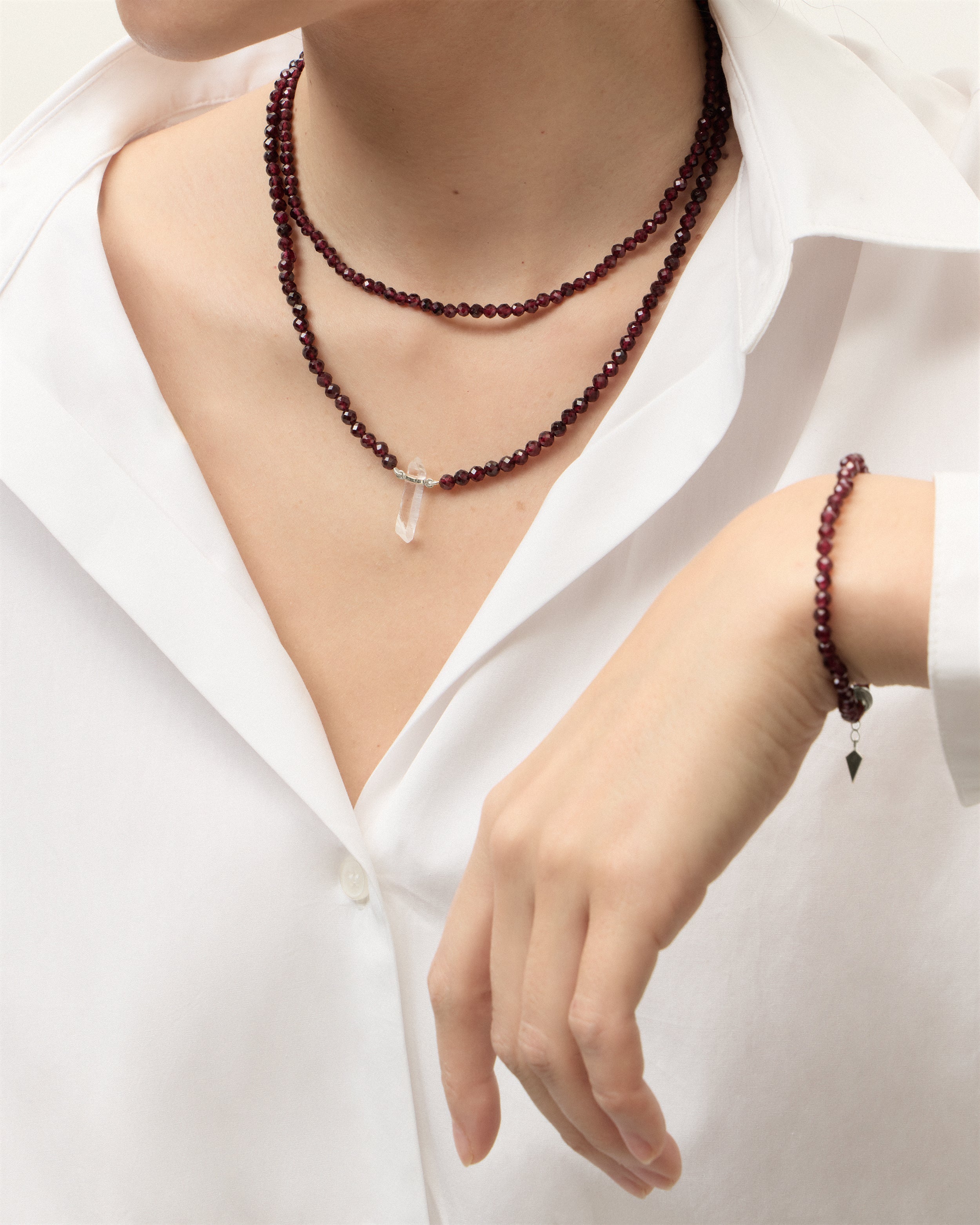 ENCARA / ETERNA INFERA Garnet necklaces and bracelet with polished silver spiral bead, extension chain and clasp, arrowhead-shaped fantasy signature, and 4 mm faceted garnet bead strand and raw polished quartz point pendant.