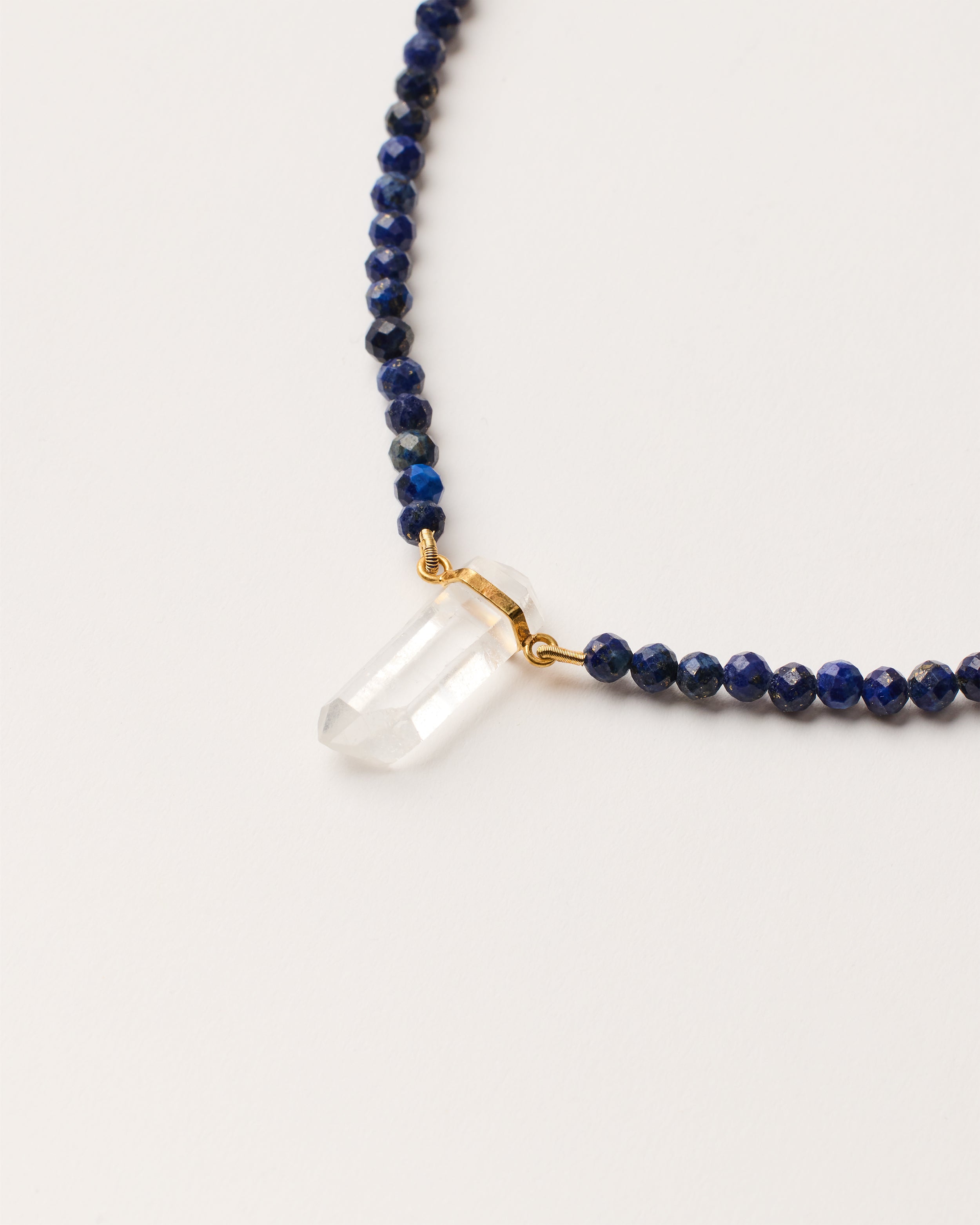 ENCARA NOCTA Lapis Lazuli necklace with raw polished quartz point pendant, gold-plated silver 8 cm extension chain and clasp, arrowhead-shaped fantasy signature, and 4 mm faceted lazurite bead strand.