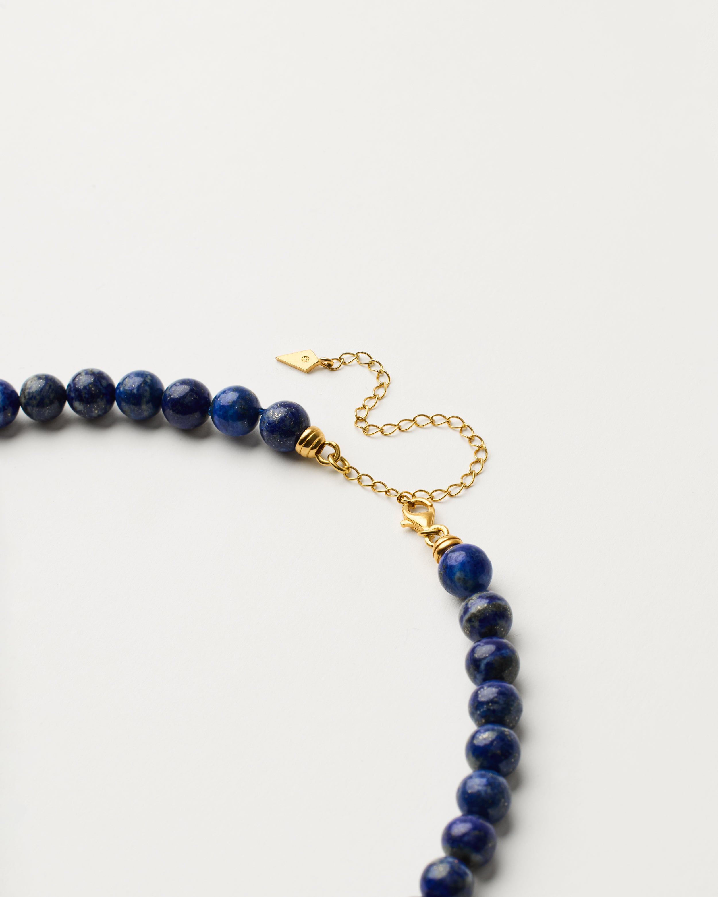 ENCARA NOCTA Lapis Lazuli necklace with raw polished quartz point pendant, gold-plated silver 8 cm extension chain and clasp, arrowhead-shaped fantasy signature, and 8 mm faceted lazurite bead strand.