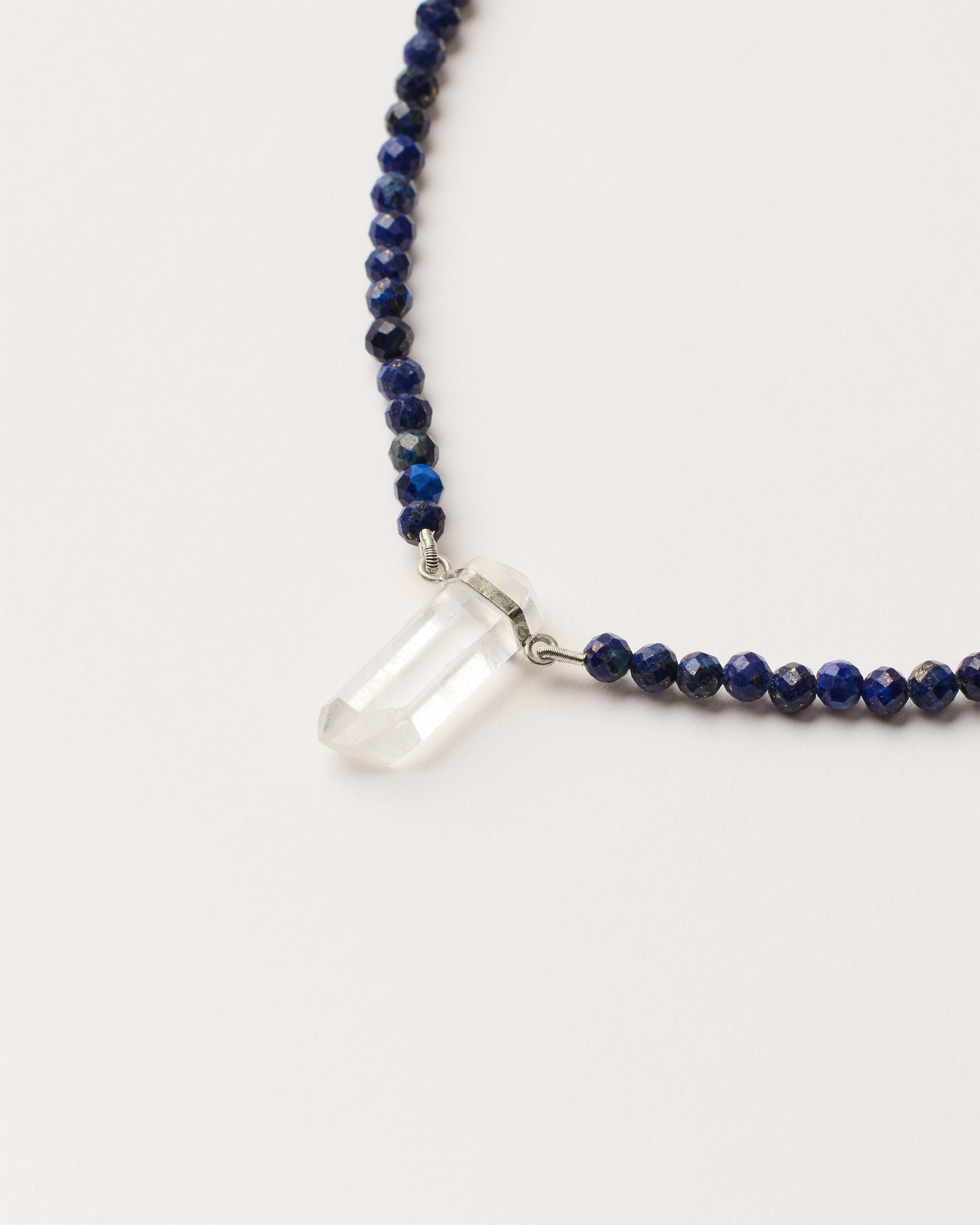 ENCARA NOCTA Lapis Lazuli necklace with raw polished quartz point pendant, silver 8 cm extension chain and clasp, arrowhead-shaped fantasy signature, and 4 mm faceted lazurite bead strand.