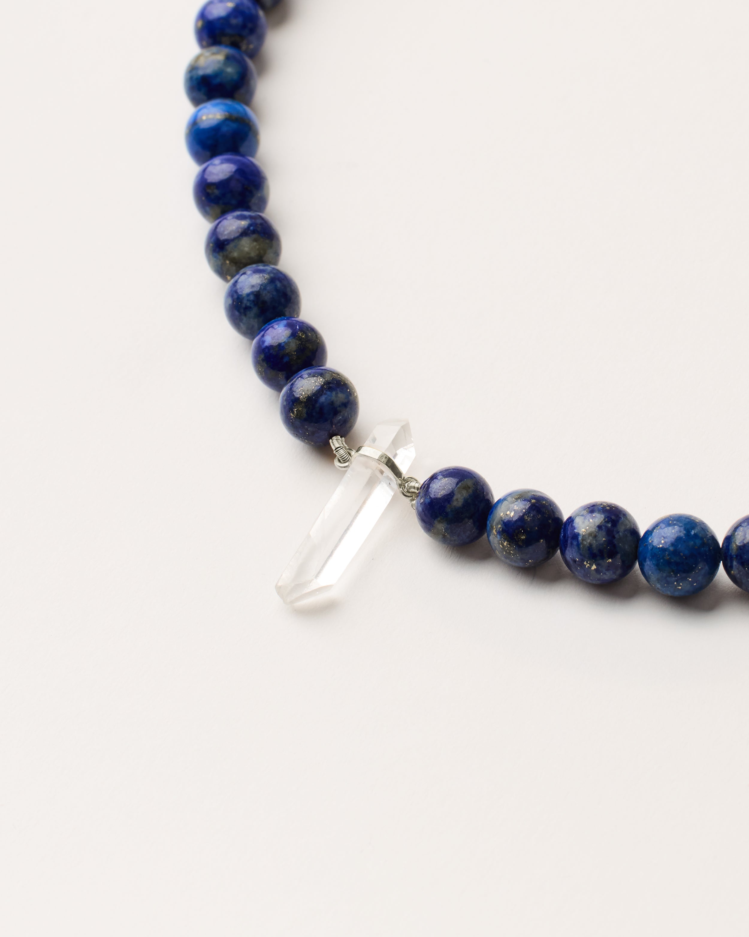 ENCARA NOCTA Lapis Lazuli necklace with raw polished quartz point pendant, silver 8 cm extension chain and clasp, arrowhead-shaped fantasy signature, and 8 mm faceted lazurite bead strand.