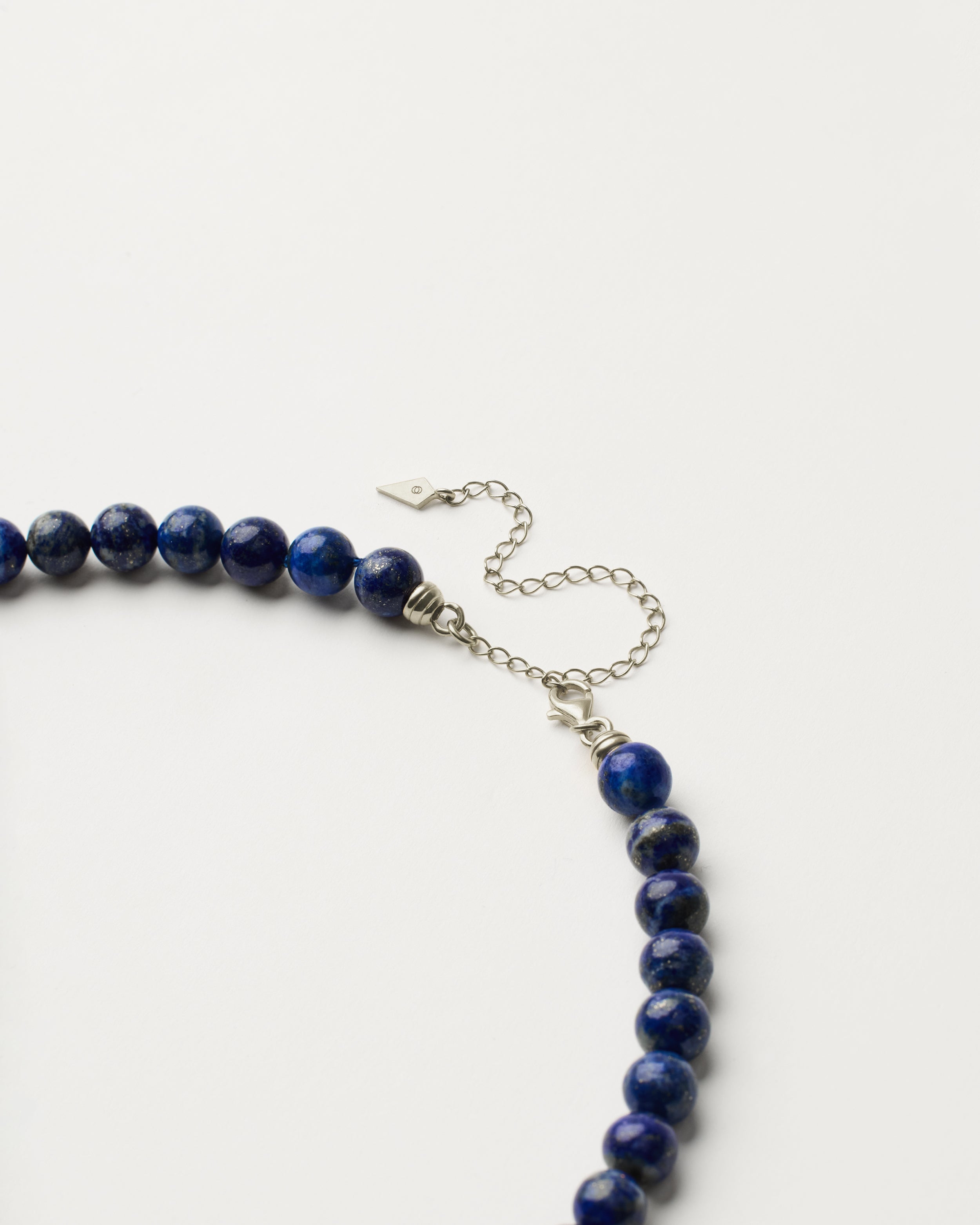 ENCARA NOCTA Lapis Lazuli necklace with raw polished quartz point pendant, silver 8 cm extension chain and clasp, arrowhead-shaped fantasy signature, and 8 mm faceted lazurite bead strand.