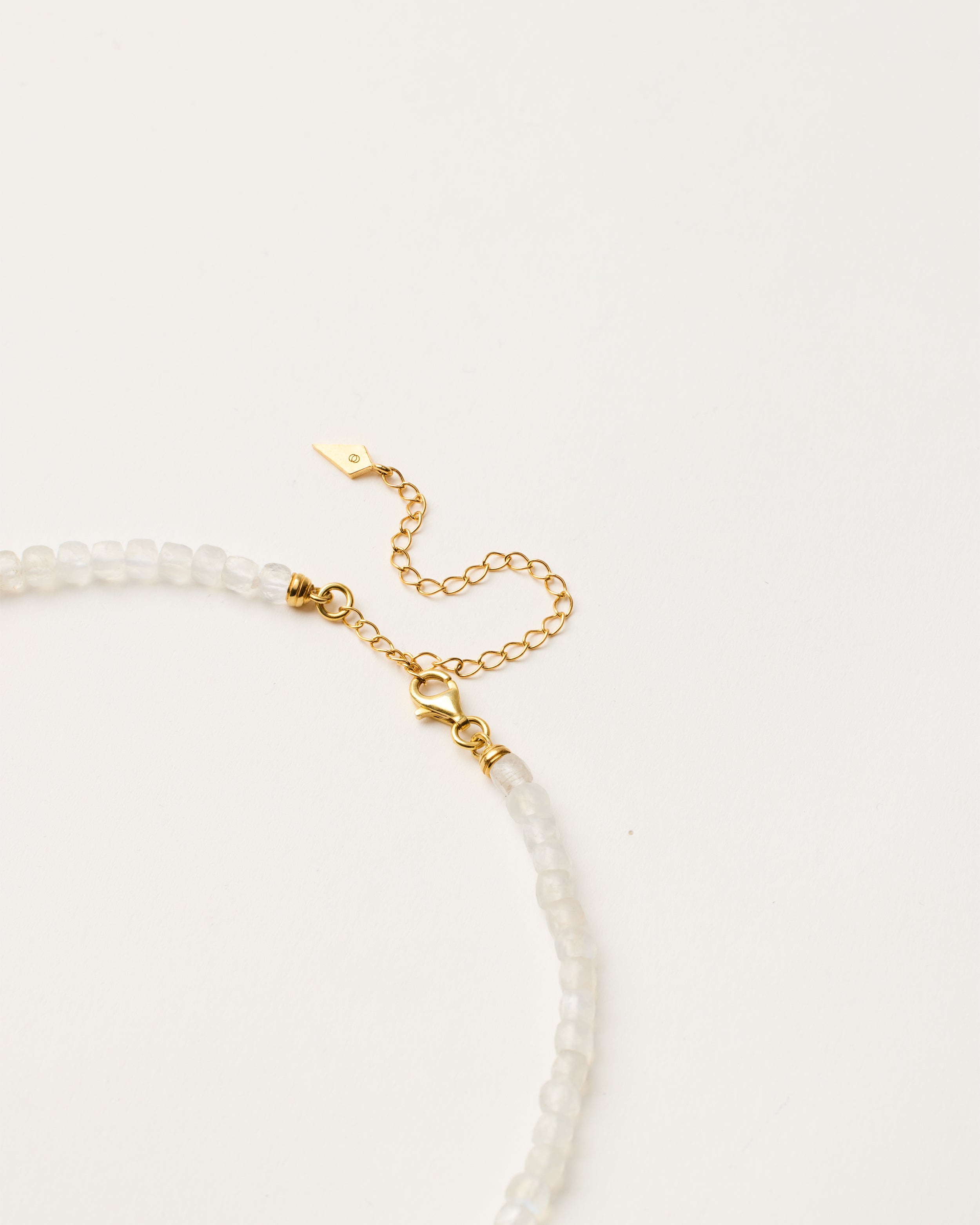 ENCARA LUNOR Moonstone necklace with raw polished quartz point pendant, gold-plated silver 8 cm extension chain and clasp, arrowhead-shaped fantasy signature, and 4 mm faceted moonstone bead strand.