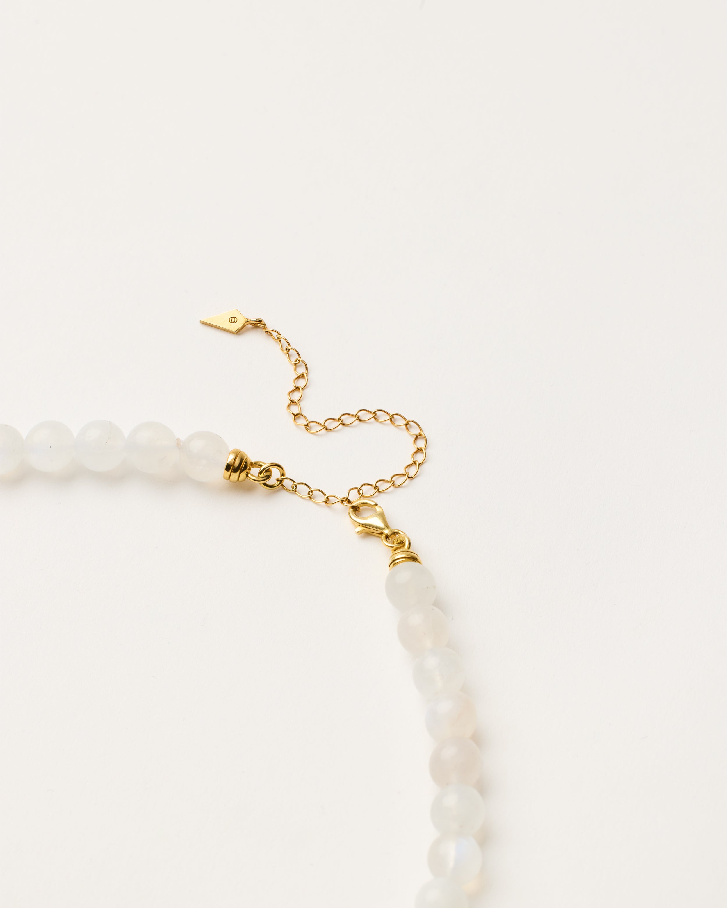 ENCARA LUNOR Moonstone necklace with raw polished quartz point pendant, gold-plated silver 8 cm extension chain and clasp, arrowhead-shaped fantasy signature, and 8 mm faceted moonstone bead strand.