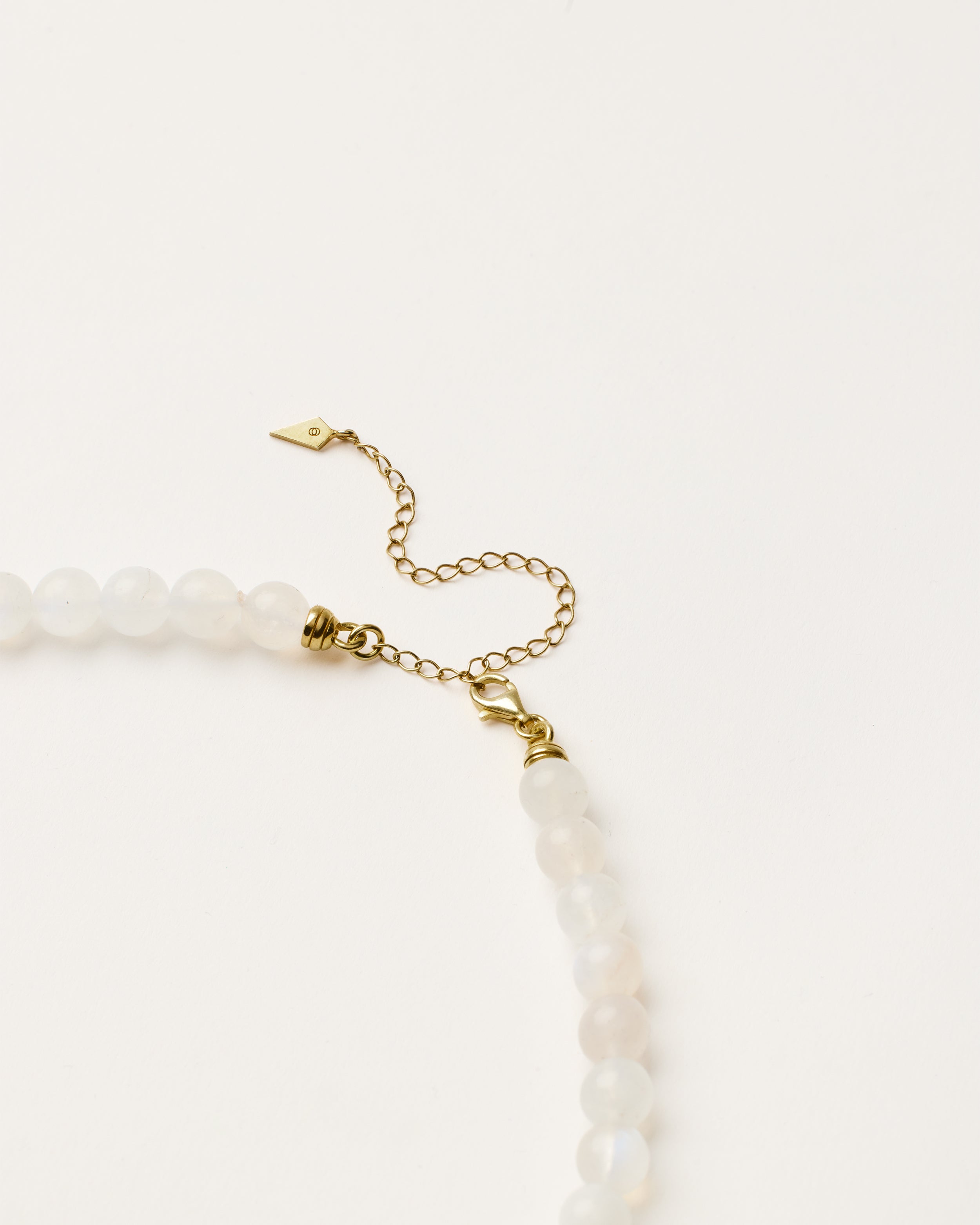 ENCARA LUNOR Moonstone necklace with raw polished quartz point pendant, gold 8 cm extension chain and clasp, arrowhead-shaped fantasy signature, and 8 mm faceted moonstone bead strand.