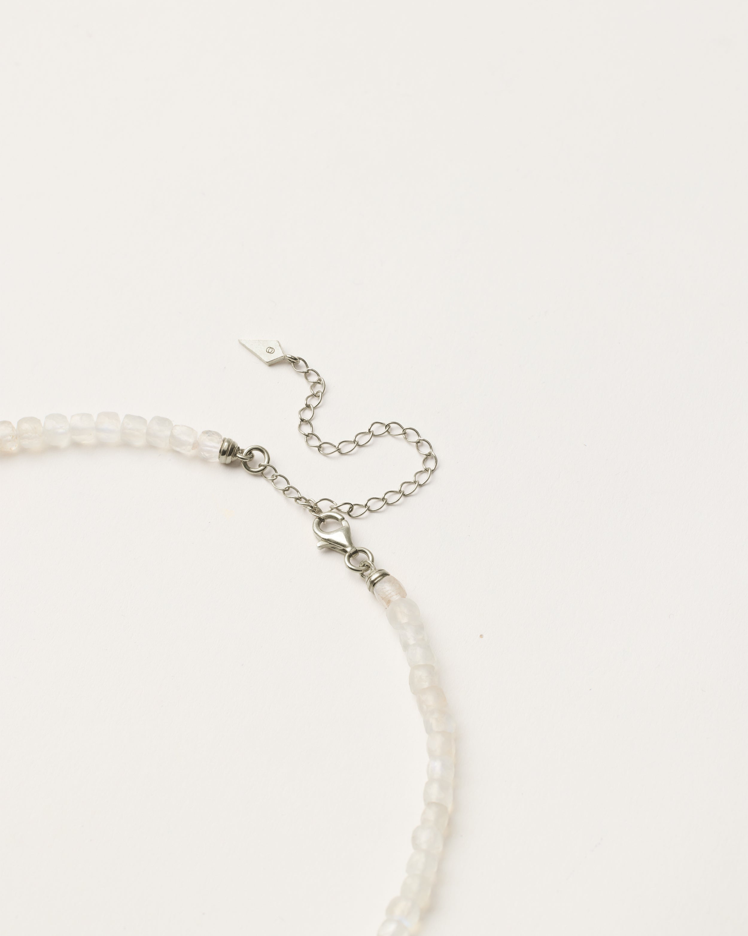 ENCARA LUNOR Moonstone necklace with raw polished quartz point pendant, silver 8 cm extension chain and clasp, arrowhead-shaped fantasy signature, and 4 mm faceted moonstone bead strand.