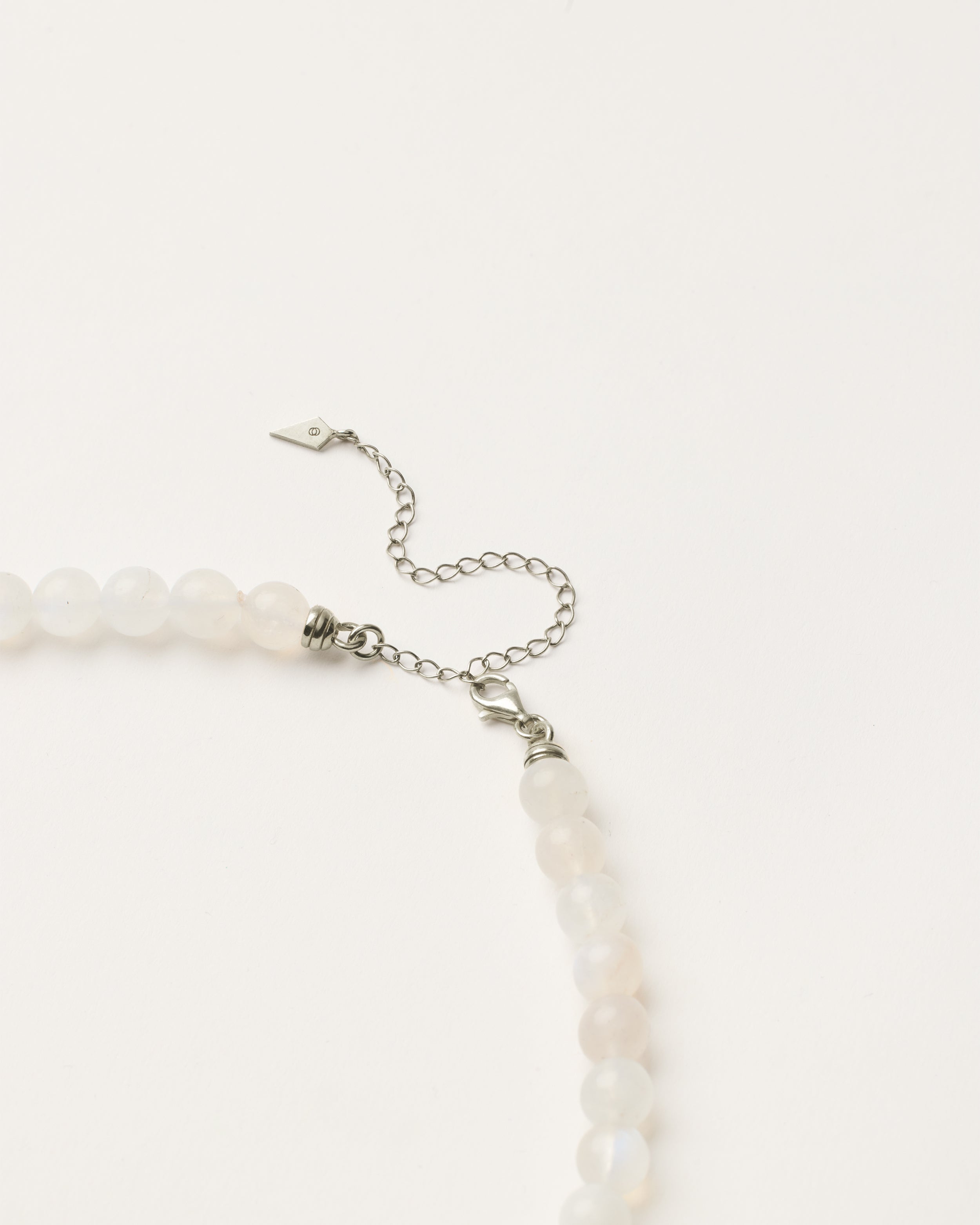 ENCARA LUNOR Moonstone necklace with raw polished quartz point pendant, silver 8 cm extension chain and clasp, arrowhead-shaped fantasy signature, and 8 mm faceted moonstone bead strand.