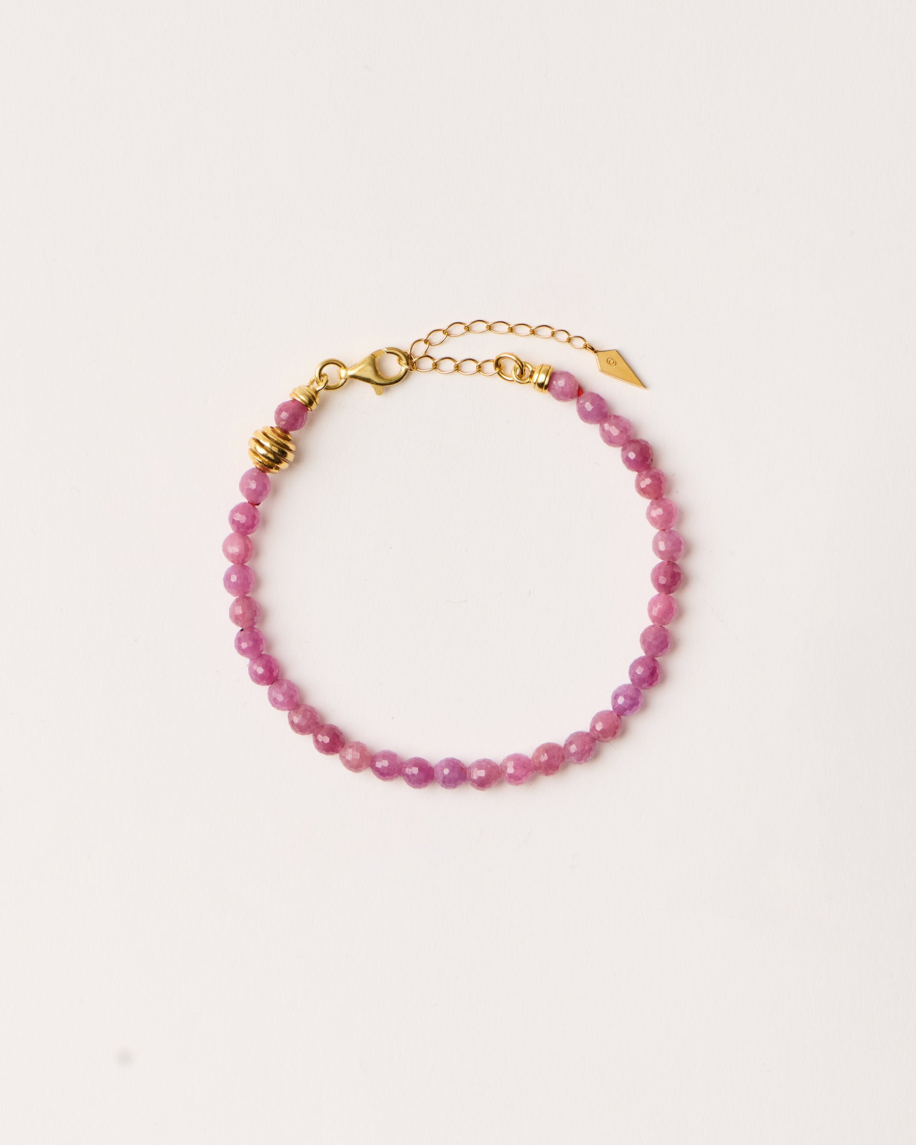 ETERNA CARMES Ruby bracelet with polished gold-plated silver spiral bead, 4 cm extension chain and clasp, arrowhead-shaped fantasy signature, and 4 mm faceted ruby bead strand.