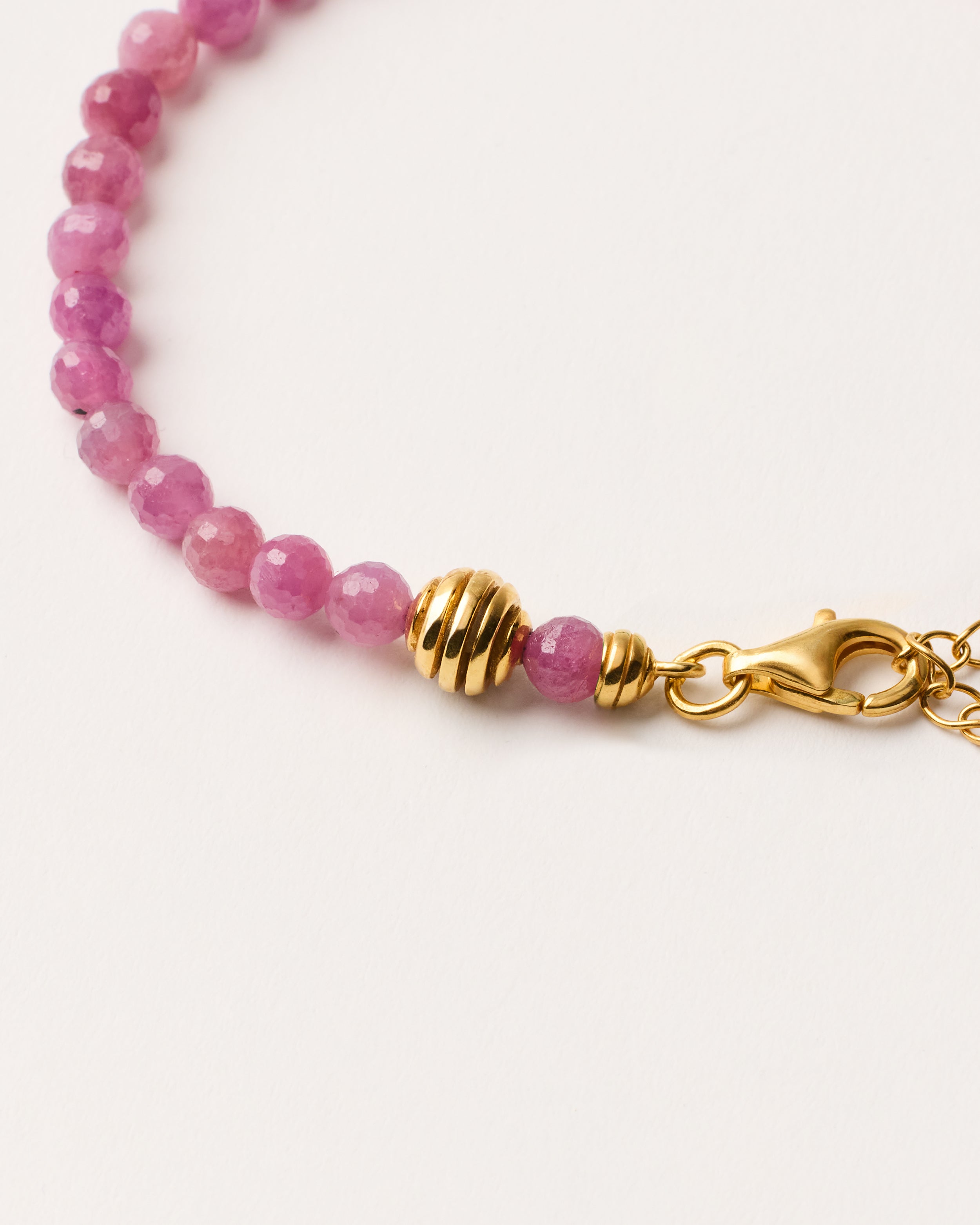 ETERNA CARMES Ruby bracelet with polished gold-plated silver spiral bead, 4 cm extension chain and clasp, arrowhead-shaped fantasy signature, and 4 mm faceted ruby bead strand.