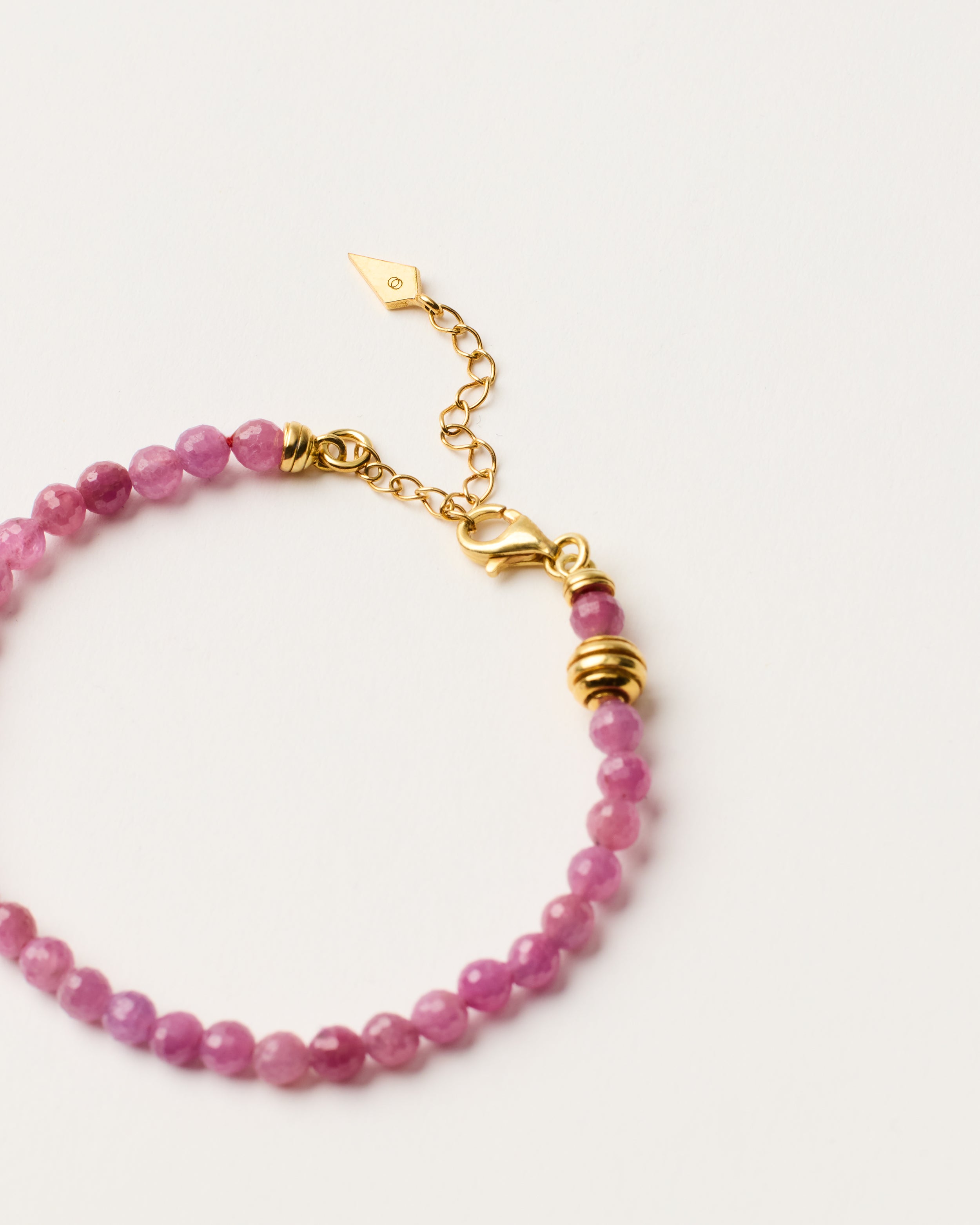ETERNA CARMES Ruby bracelet with polished gold-plated silver spiral bead, 4 cm extension chain and clasp, arrowhead-shaped fantasy signature, and 4 mm faceted ruby bead strand.
