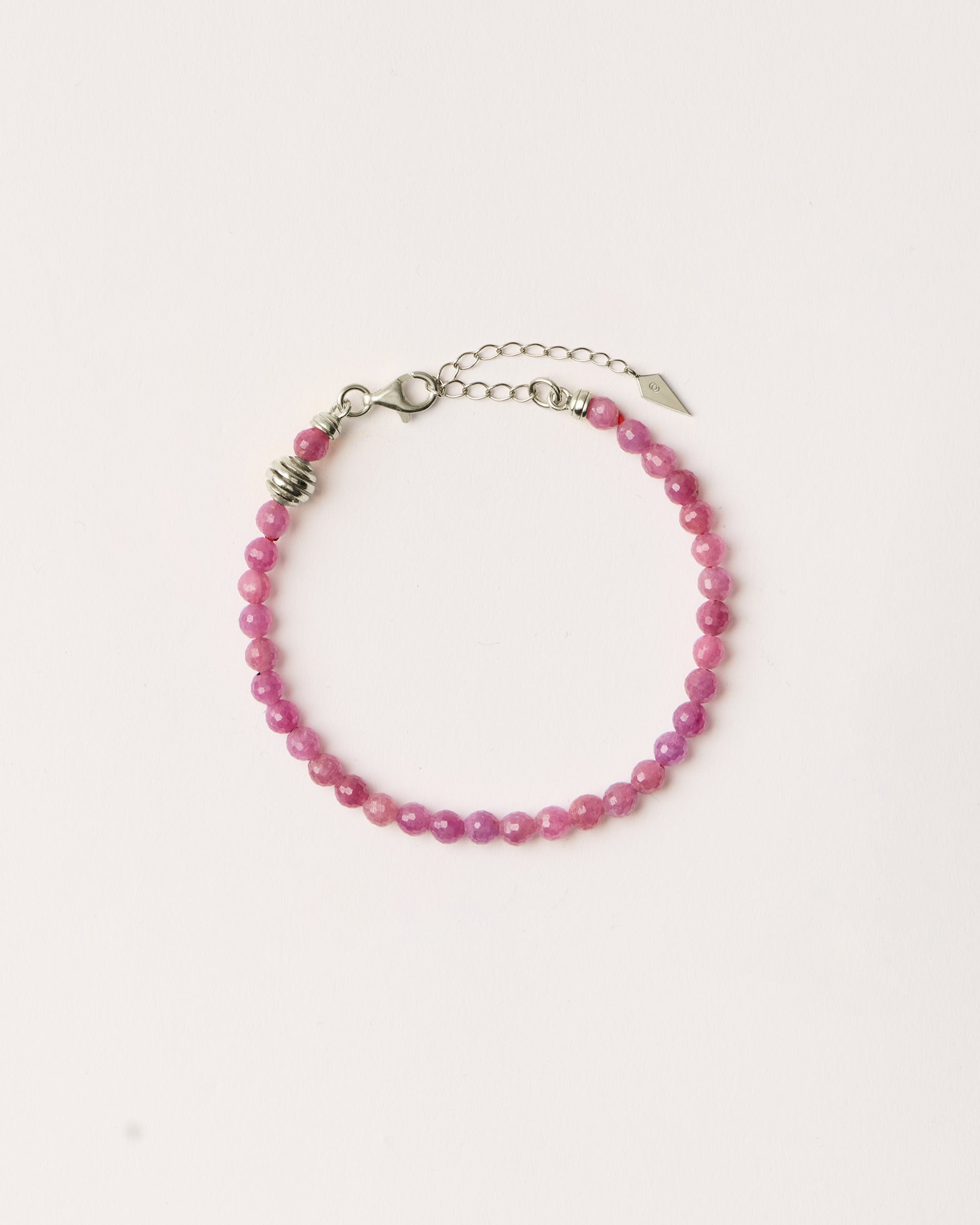 ETERNA CARMES Ruby bracelet with polished silver spiral bead, 4 cm extension chain and clasp, arrowhead-shaped fantasy signature, and 4 mm faceted ruby bead strand.