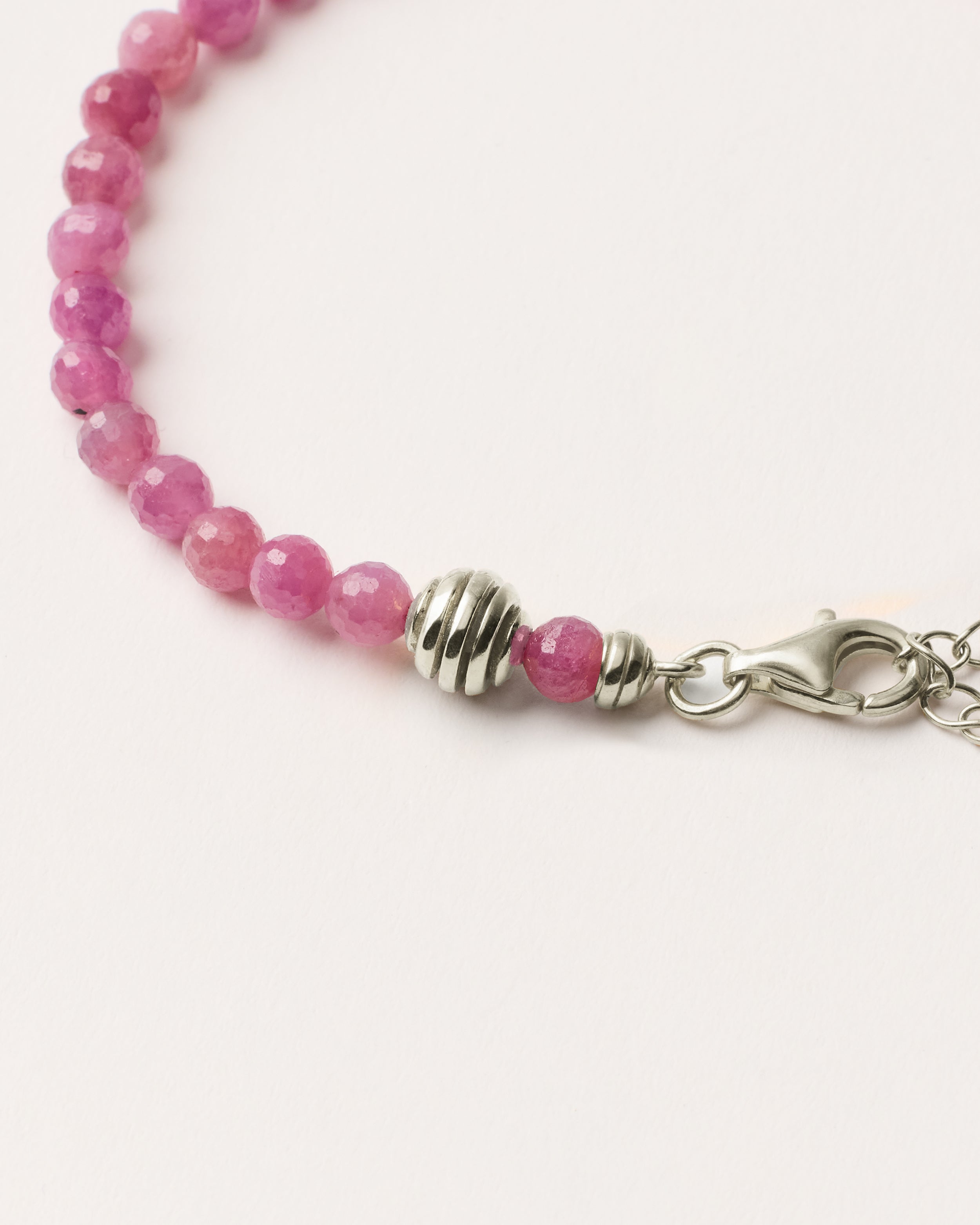 ETERNA CARMES Ruby bracelet with polished silver spiral bead, 4 cm extension chain and clasp, arrowhead-shaped fantasy signature, and 4 mm faceted ruby bead strand.