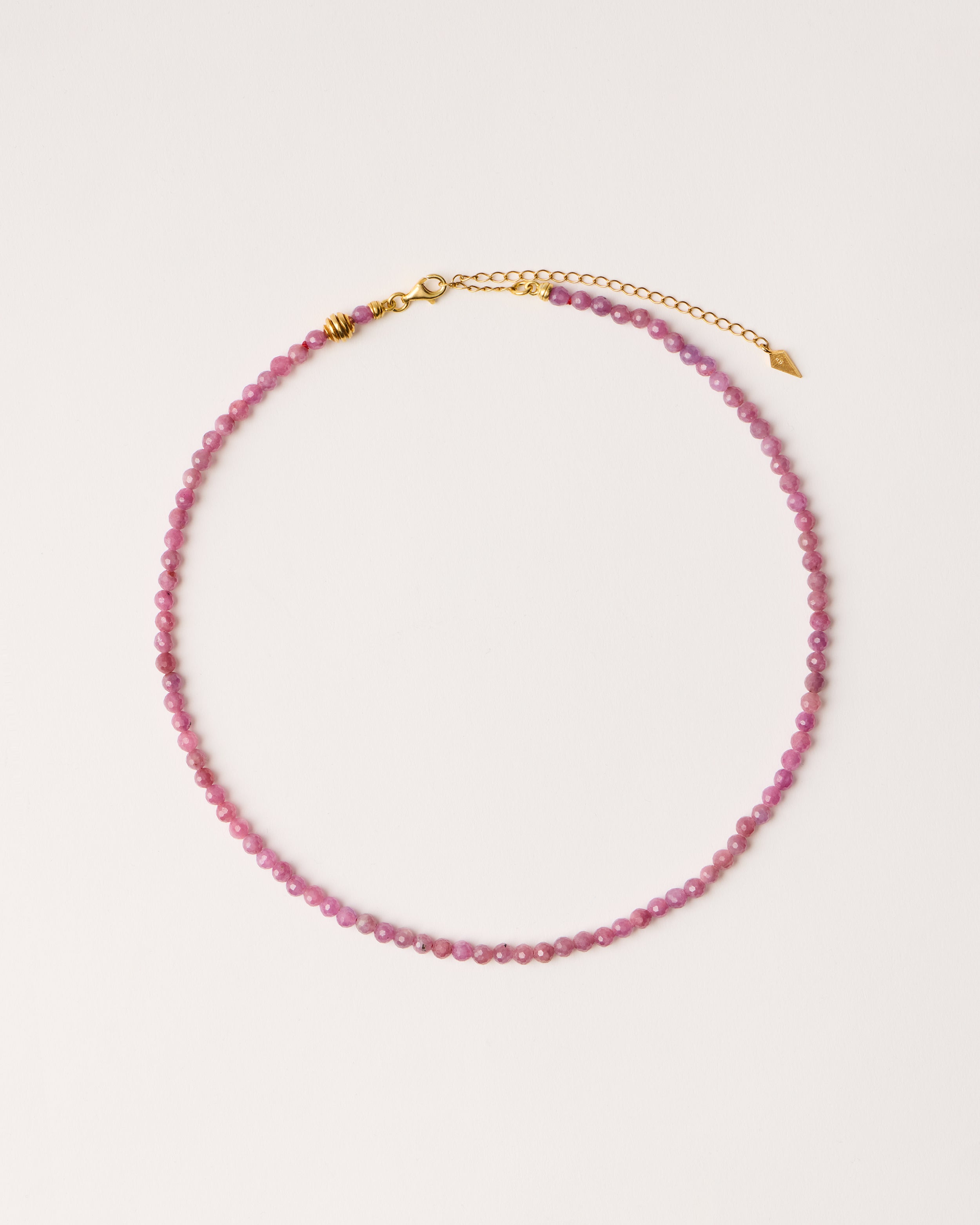 ETERNA CARMES Ruby necklace with polished gold-plated silver spiral bead, 8 cm extension chain and clasp, arrowhead-shaped fantasy signature, and 4 mm faceted ruby bead strand.