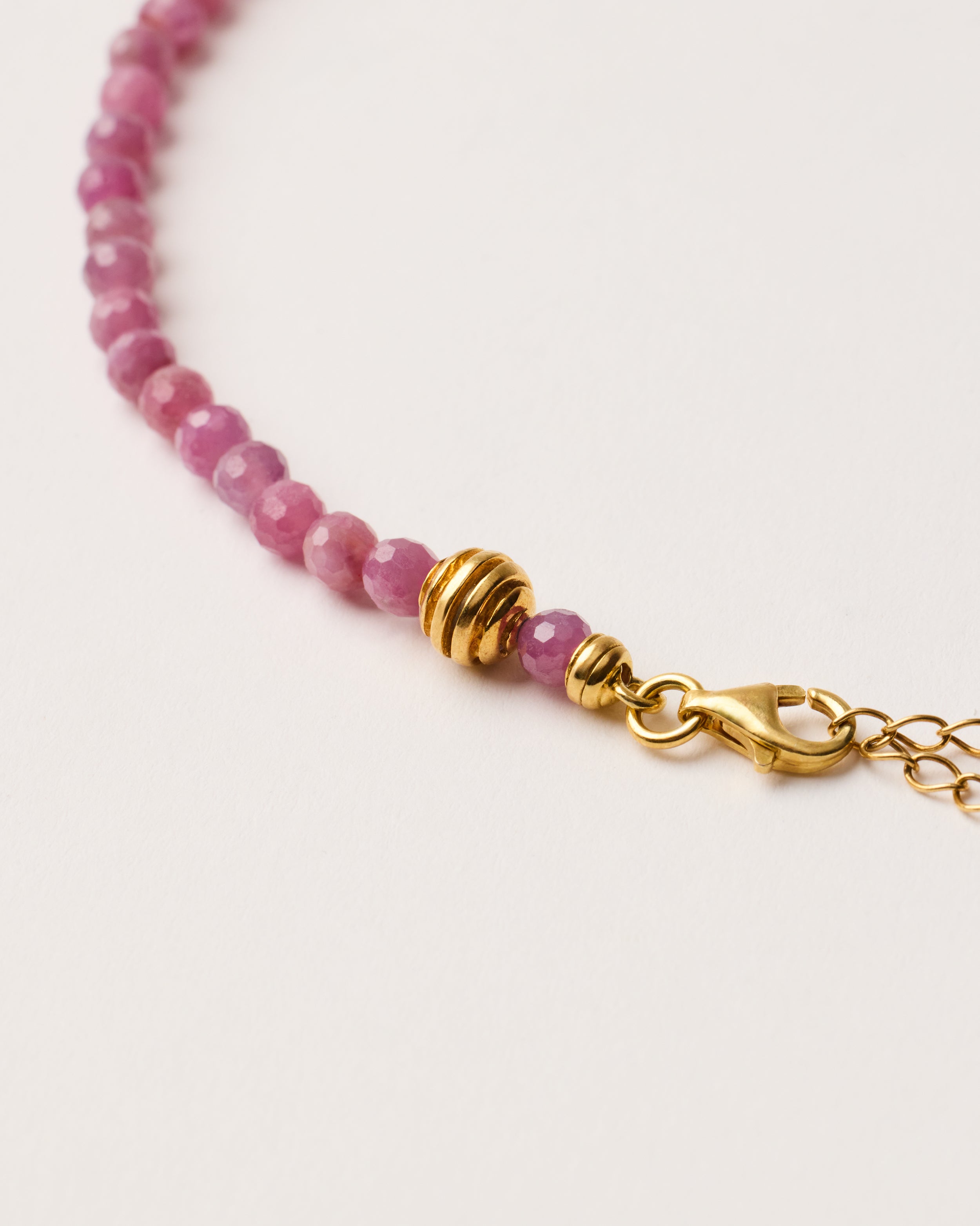 ETERNA CARMES Ruby necklace with polished gold-plated silver spiral bead, 8 cm extension chain and clasp, arrowhead-shaped fantasy signature, and 4 mm faceted ruby bead strand.