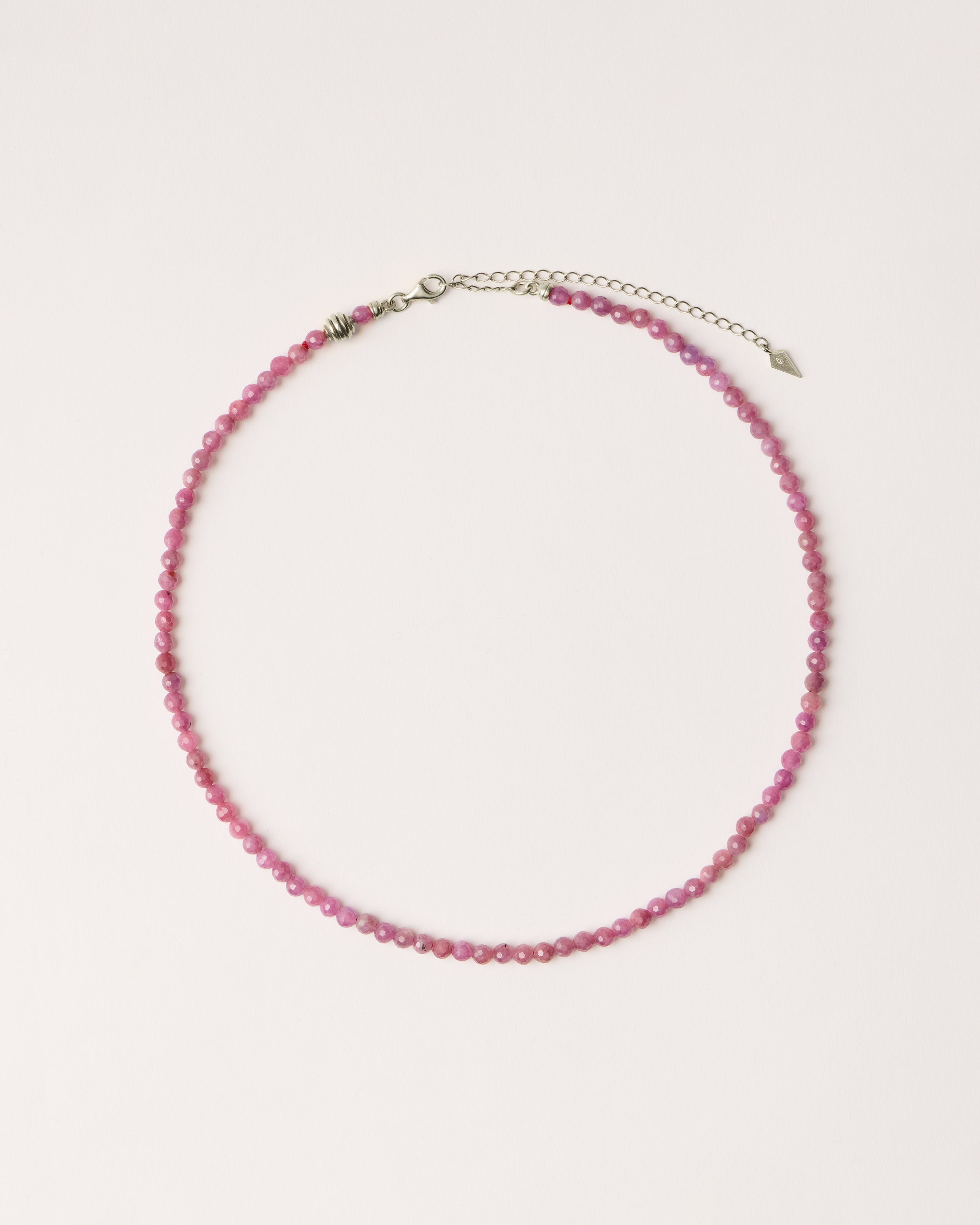 ETERNA CARMES Ruby necklace with polished silver spiral bead, 8 cm extension chain and clasp, arrowhead-shaped fantasy signature, and 4 mm faceted ruby bead strand.