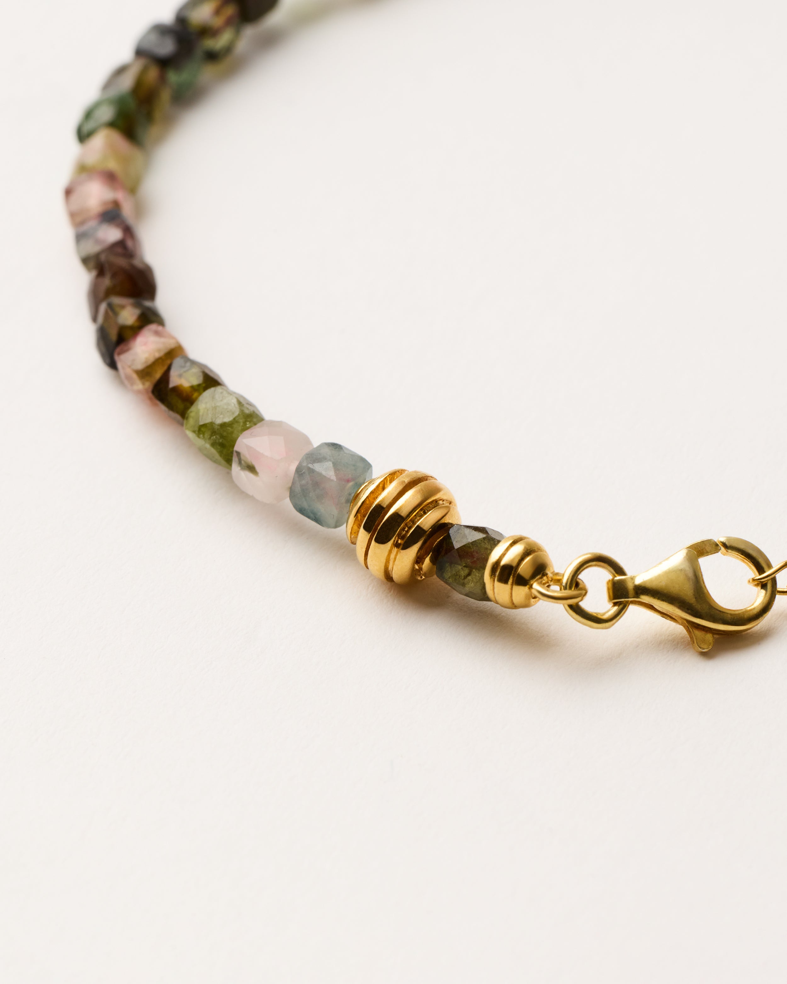 ETERNA AURIL Tourmaline bracelet with polished gold-plated silver spiral bead, 4 cm extension chain and clasp, arrowhead-shaped fantasy signature, and 4 mm faceted tourmaline bead strand.