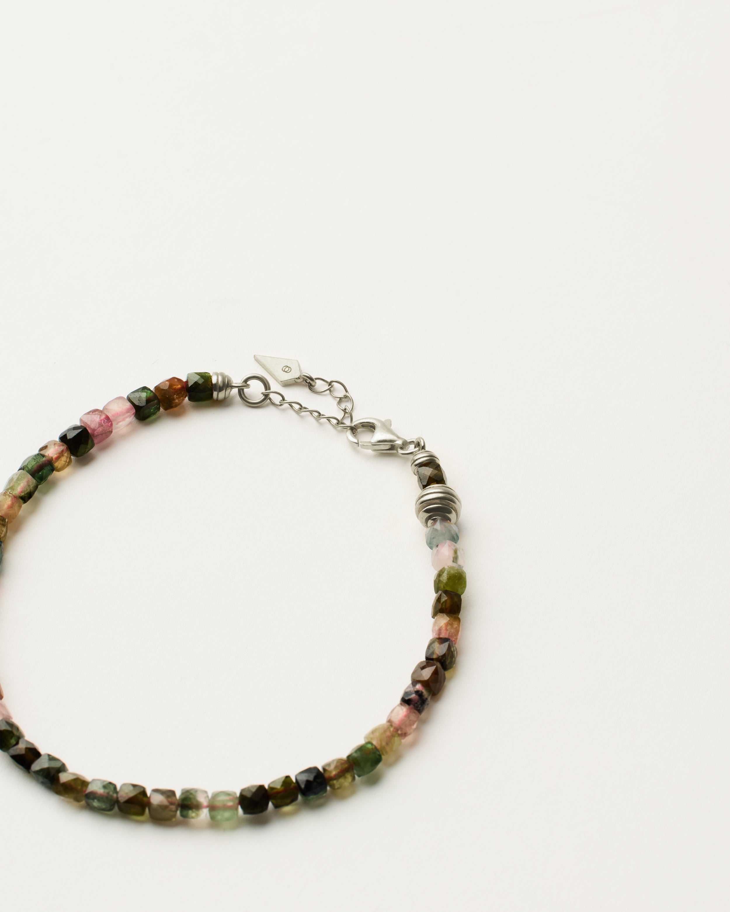 ETERNA AURIL Tourmaline bracelet with polished silver spiral bead, 4 cm extension chain and clasp, arrowhead-shaped fantasy signature, and 4 mm faceted tourmaline bead strand.