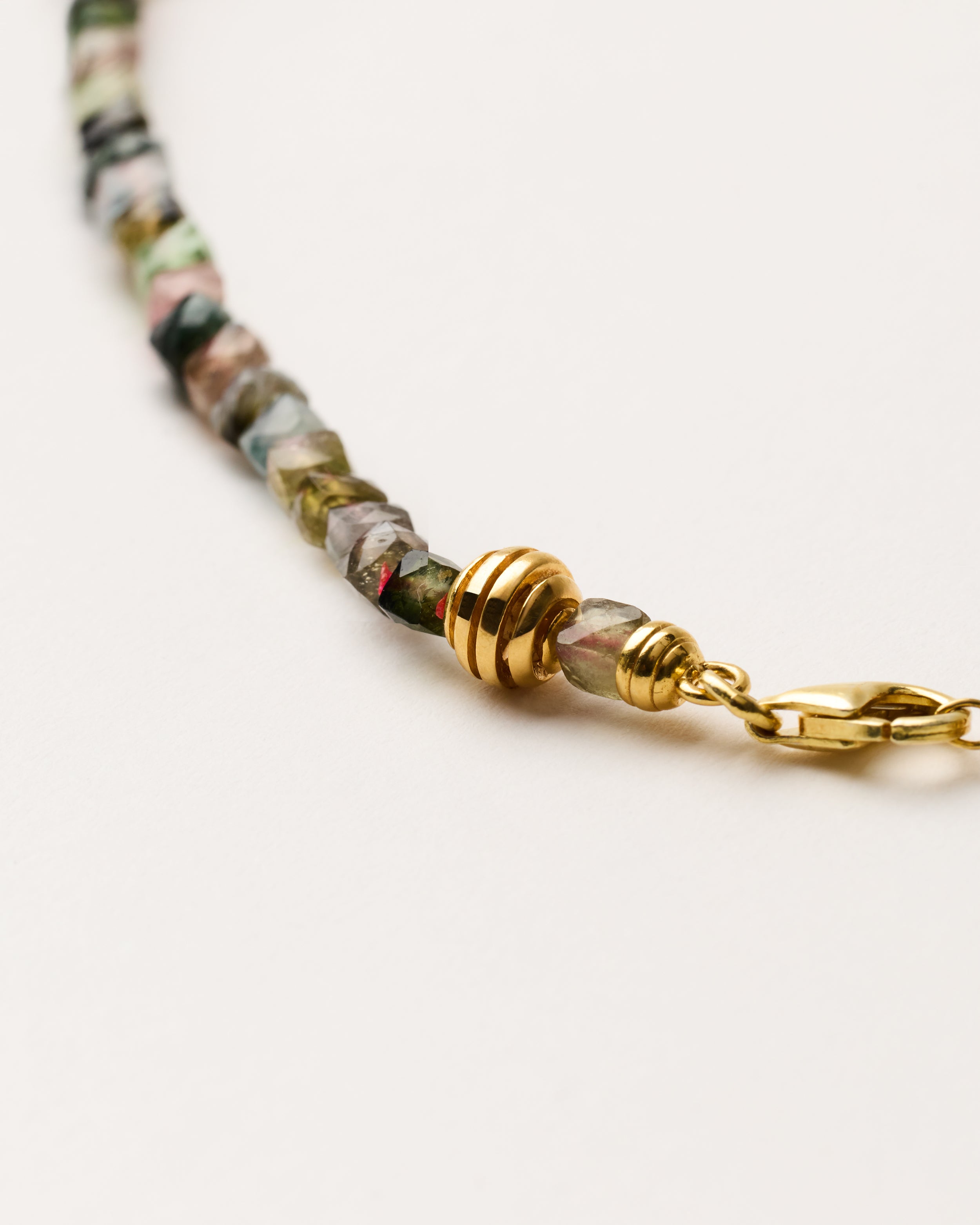 ETERNA AURIL Tourmaline necklace with polished gold-plated silver spiral bead, 8 cm extension chain and clasp, arrowhead-shaped fantasy signature, and 4 mm faceted tourmaline bead strand.