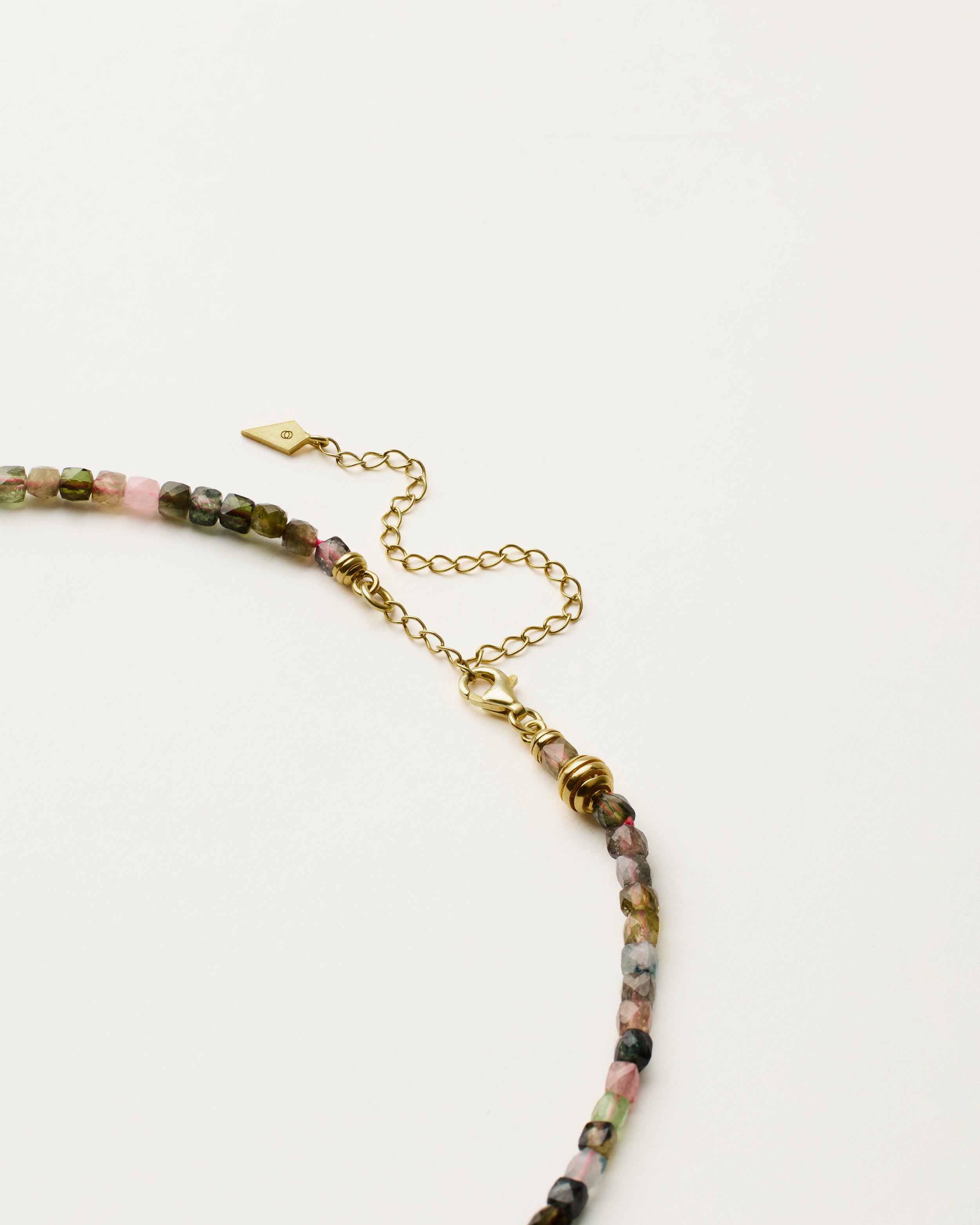 ETERNA AURIL Tourmaline necklace with polished gold spiral bead, 8 cm extension chain and clasp, arrowhead-shaped fantasy signature, and 4 mm faceted tourmaline bead strand.