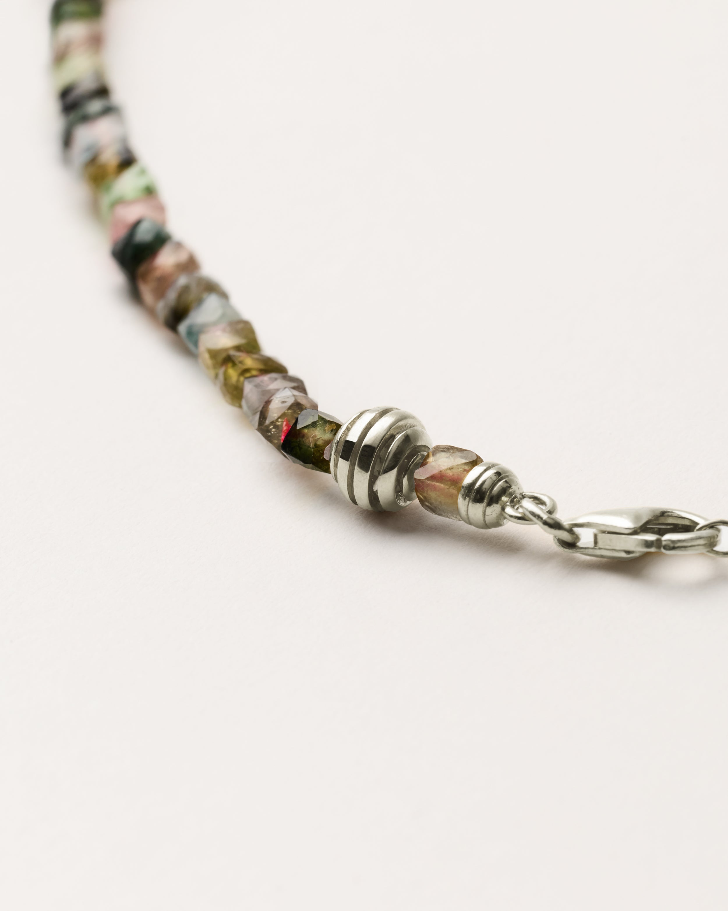 ETERNA AURIL Tourmaline necklace with polished silver spiral bead, 8 cm extension chain and clasp, arrowhead-shaped fantasy signature, and 4 mm faceted tourmaline bead strand.