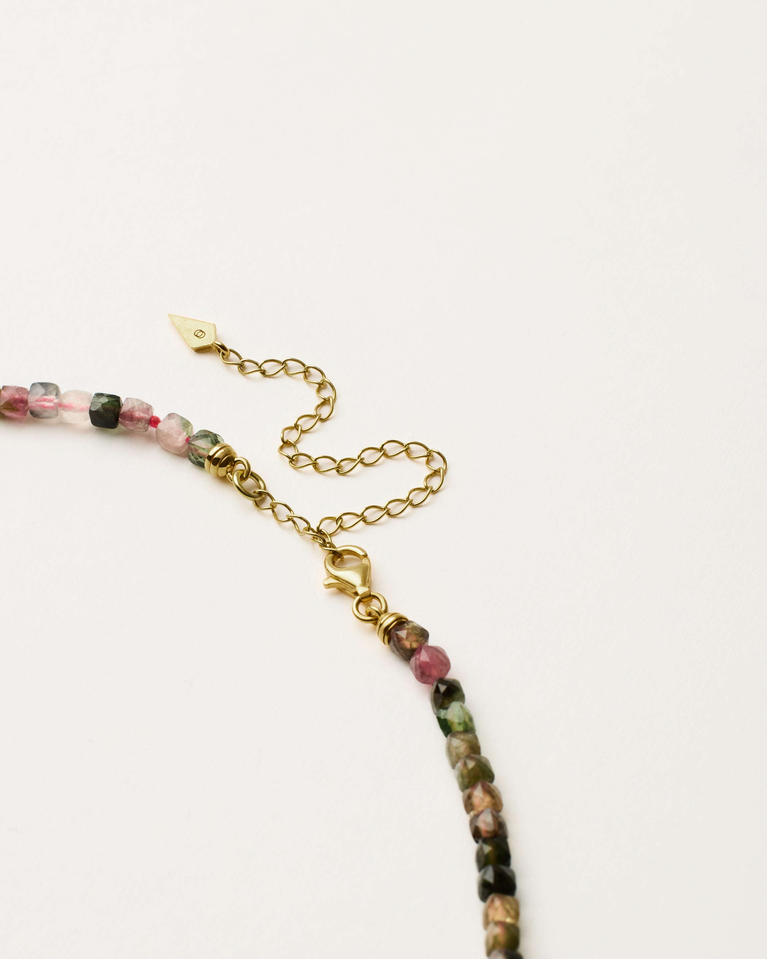 ENCARA AURIL Tourmaline necklace with raw polished quartz point pendant, gold 8 cm extension chain and clasp, arrowhead-shaped fantasy signature, and 4 mm faceted tourmaline bead strand.