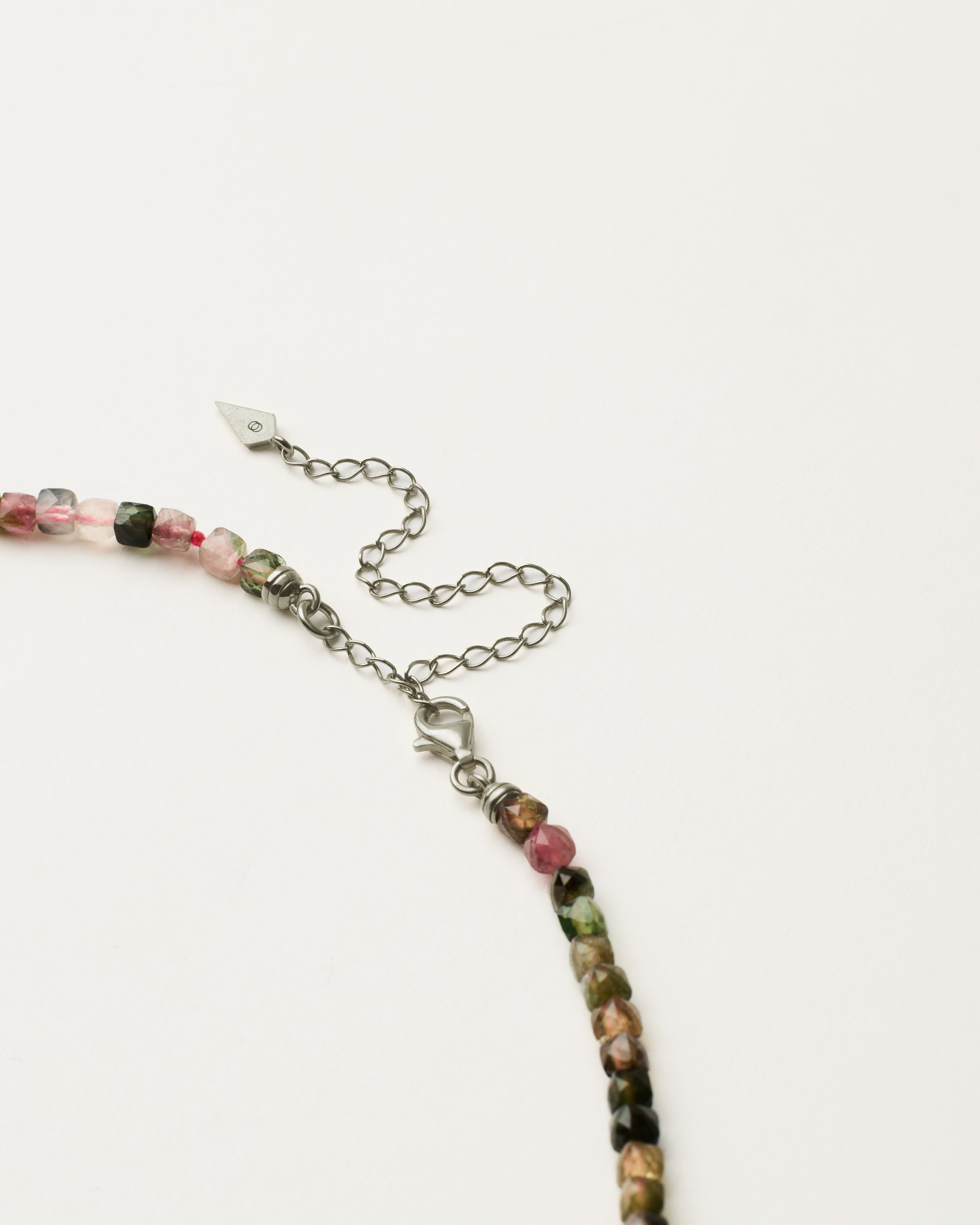 ENCARA AURIL Tourmaline necklace with raw polished quartz point pendant, silver 8 cm extension chain and clasp, arrowhead-shaped fantasy signature, and 4 mm faceted tourmaline bead strand.