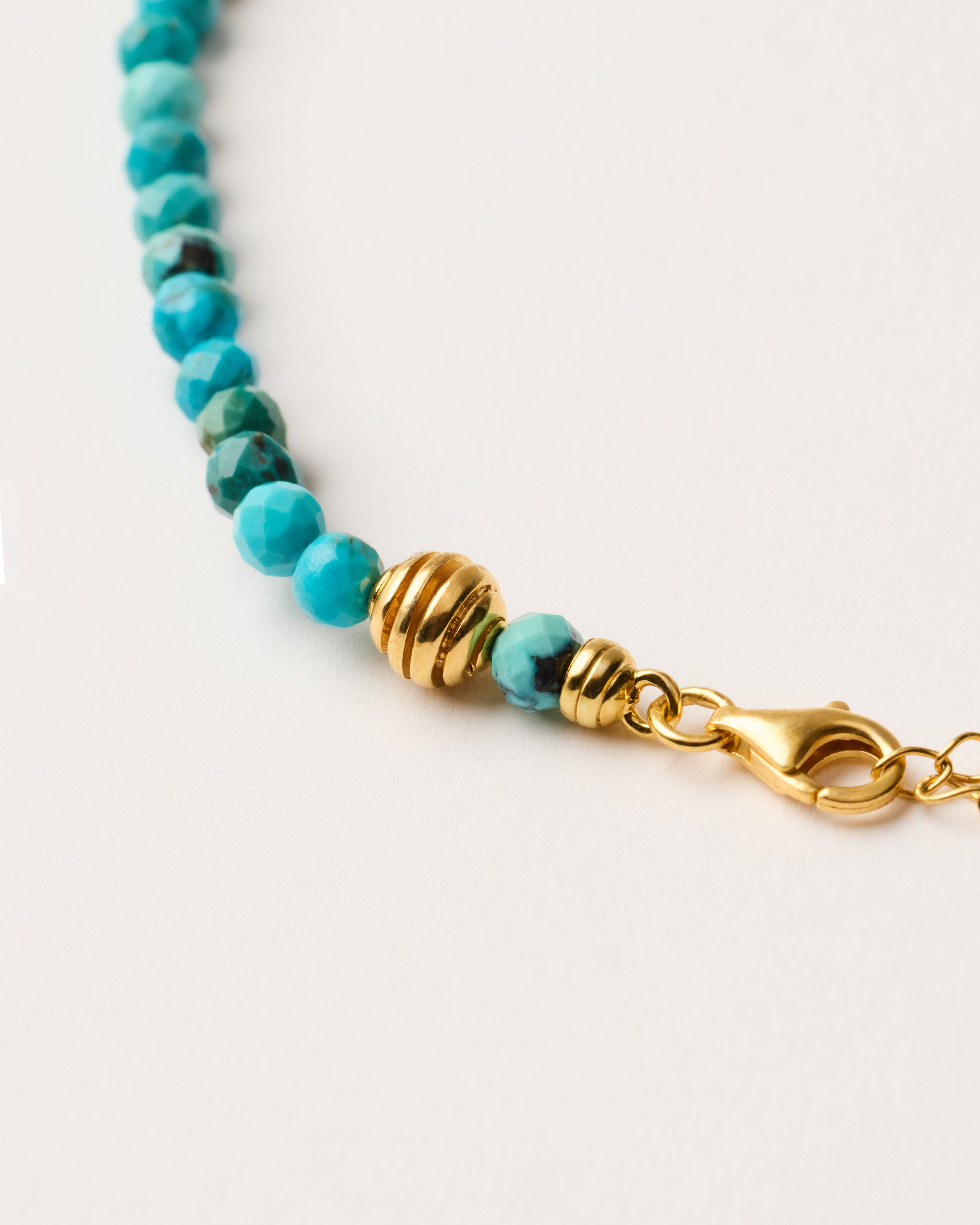 ETERNA AZURA Turquoise necklace with polished gold-plated silver spiral bead, 8 cm extension chain and clasp, arrowhead-shaped fantasy signature, and 4 mm faceted turquoise bead strand.