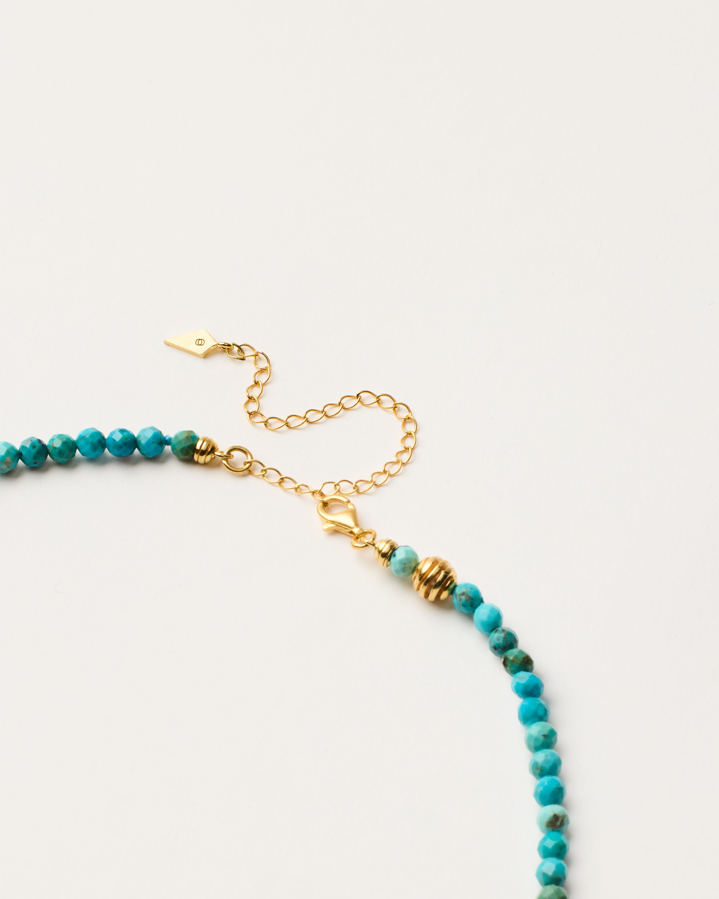 ETERNA AZURA Turquoise necklace with polished gold-plated silver spiral bead, 8 cm extension chain and clasp, arrowhead-shaped fantasy signature, and 4 mm faceted turquoise bead strand.