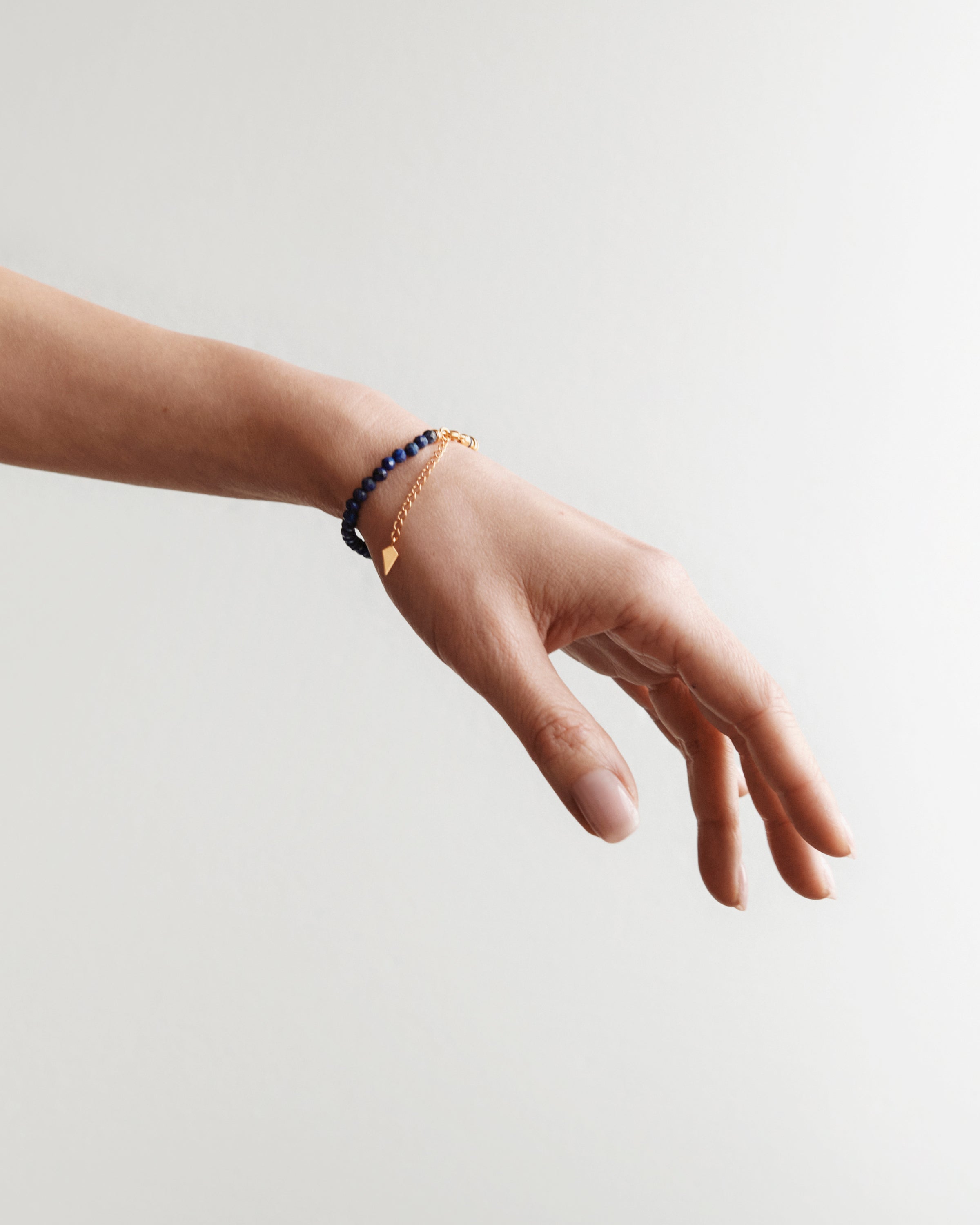 ETERNA NOCTA Lapis Lazuli bracelet with polished gold spiral bead, 4 cm extension chain and clasp, arrowhead-shaped fantasy signature, and 4 mm faceted lazurite bead strand.