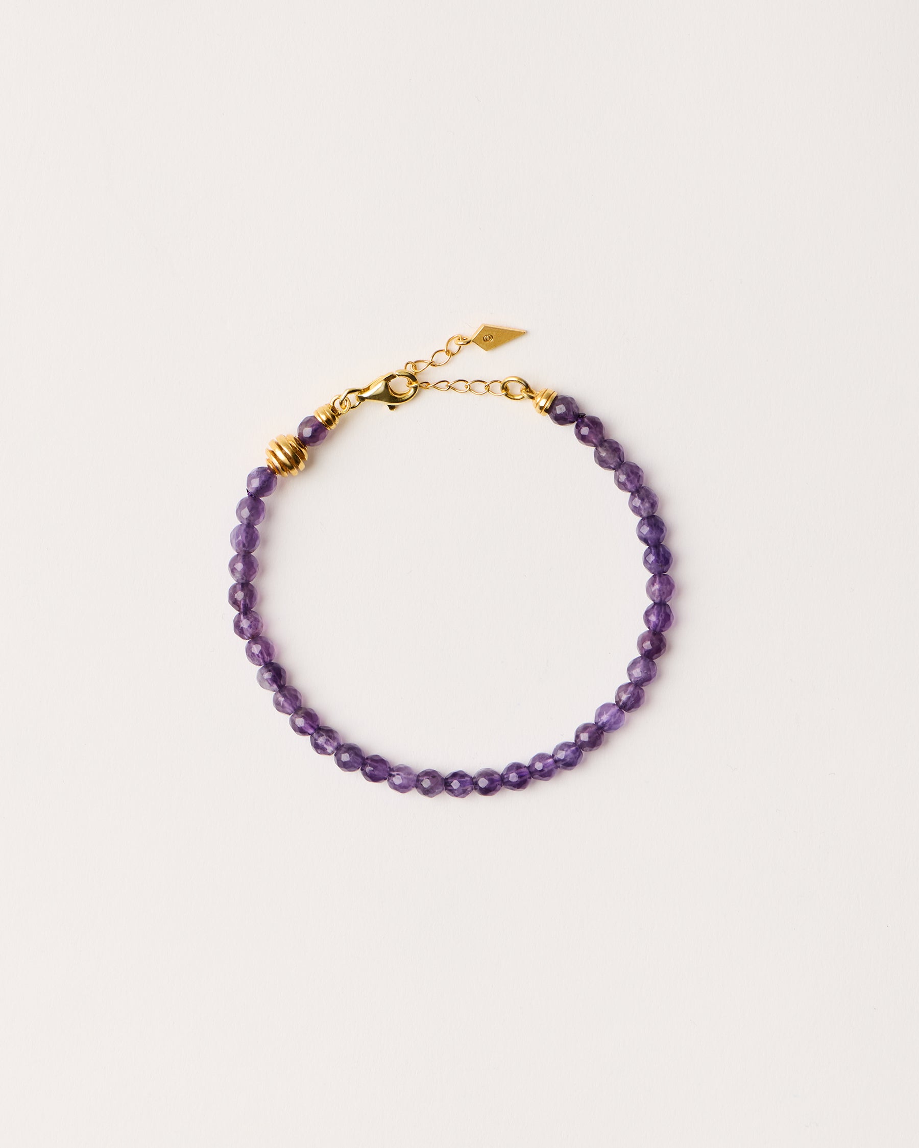 ETERNA VÉLA Amethyst bracelet with polished gold-plated silver spiral bead, 4 cm extension chain and clasp, arrowhead-shaped fantasy signature, and 4 mm faceted amethyst bead strand.