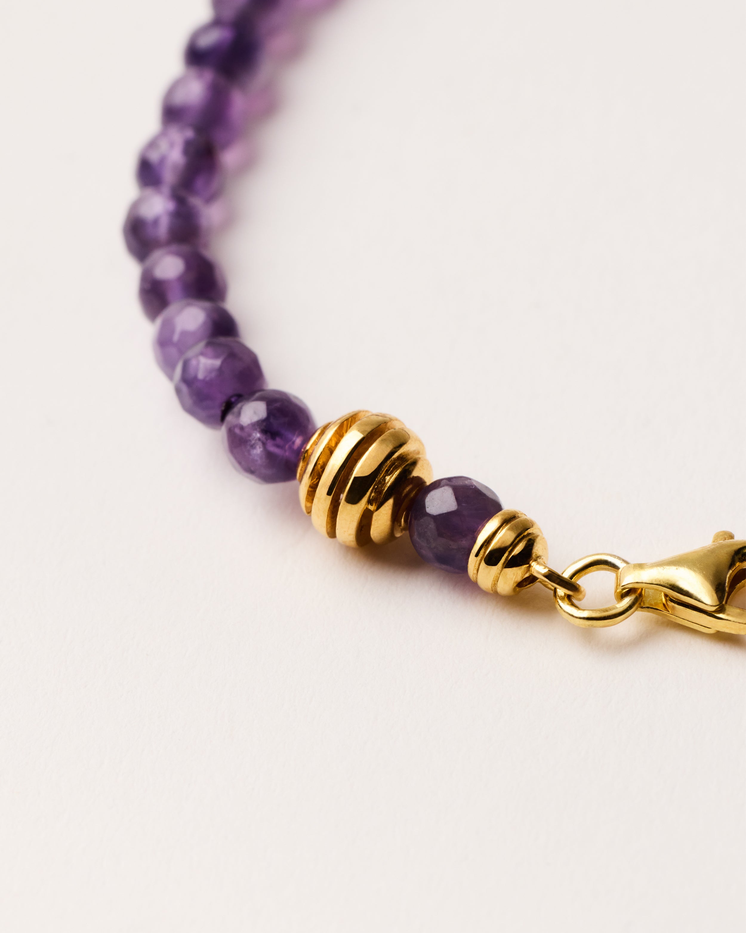 ETERNA VÉLA Amethyst bracelet with polished gold-plated silver spiral bead, 4 cm extension chain and clasp, arrowhead-shaped fantasy signature, and 4 mm faceted amethyst bead strand.