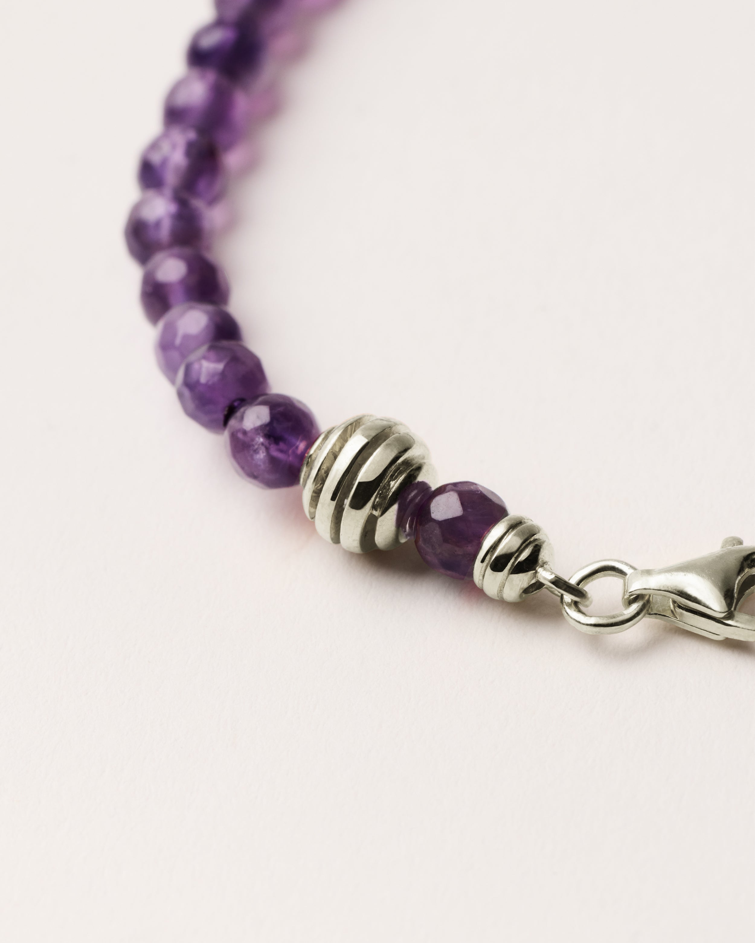 ETERNA VÉLA Amethyst bracelet with polished silver spiral bead, 4 cm extension chain and clasp, arrowhead-shaped fantasy signature, and 4 mm faceted amethyst bead strand.