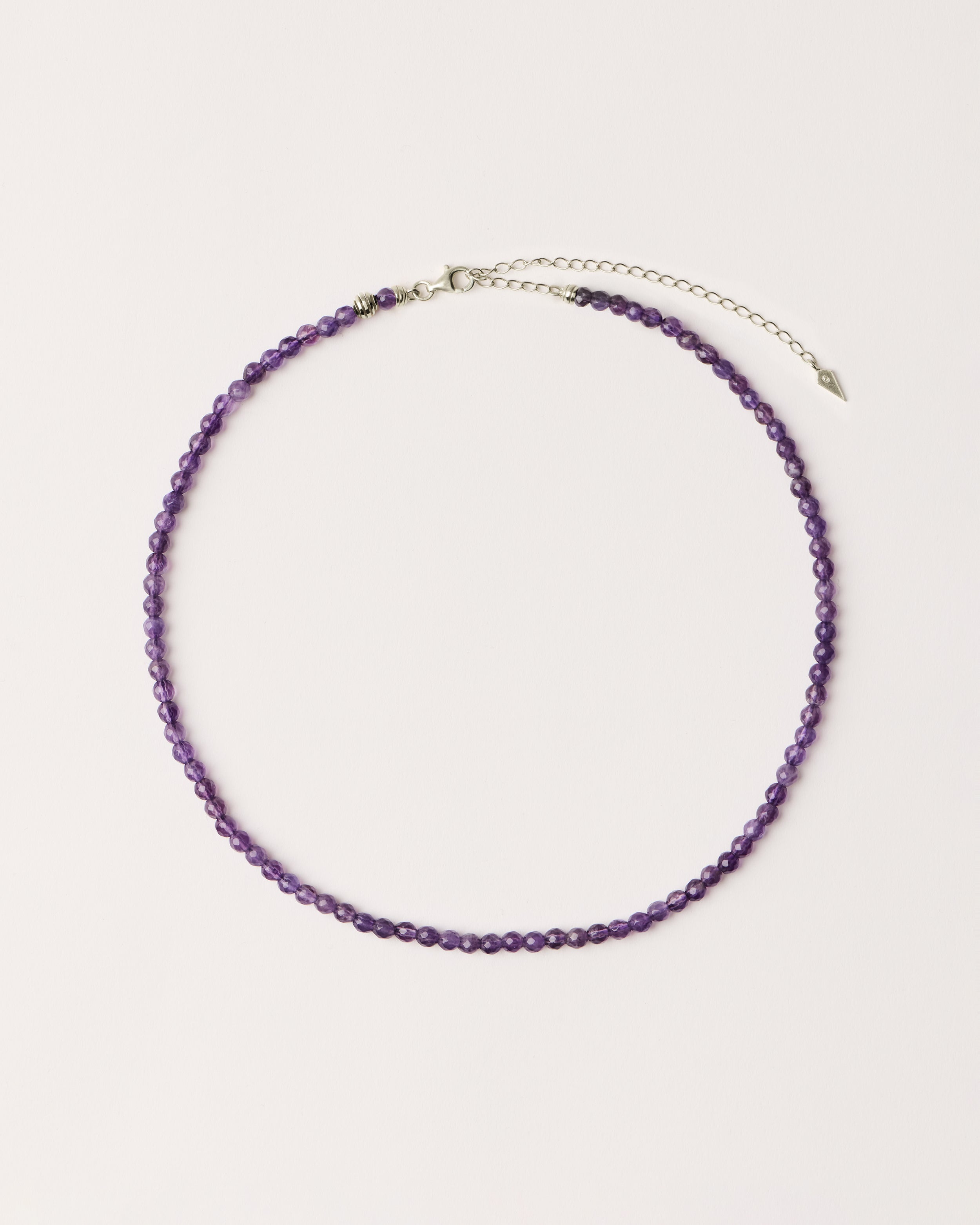 ETERNA VÉLA Amethyst necklace with polished silver spiral bead, 8 cm extension chain and clasp, arrowhead-shaped fantasy signature, and 4 mm faceted amethyst bead strand.