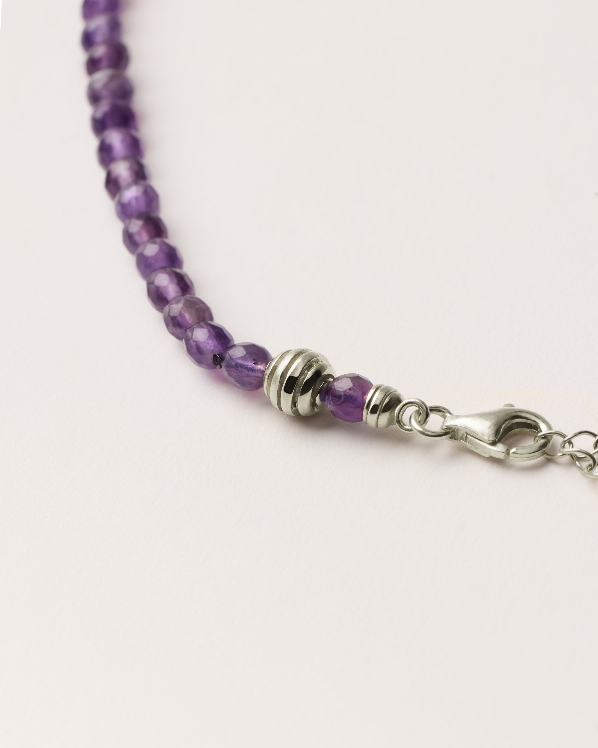 ETERNA VÉLA Amethyst necklace with polished silver spiral bead, 8 cm extension chain and clasp, arrowhead-shaped fantasy signature, and 4 mm faceted amethyst bead strand.