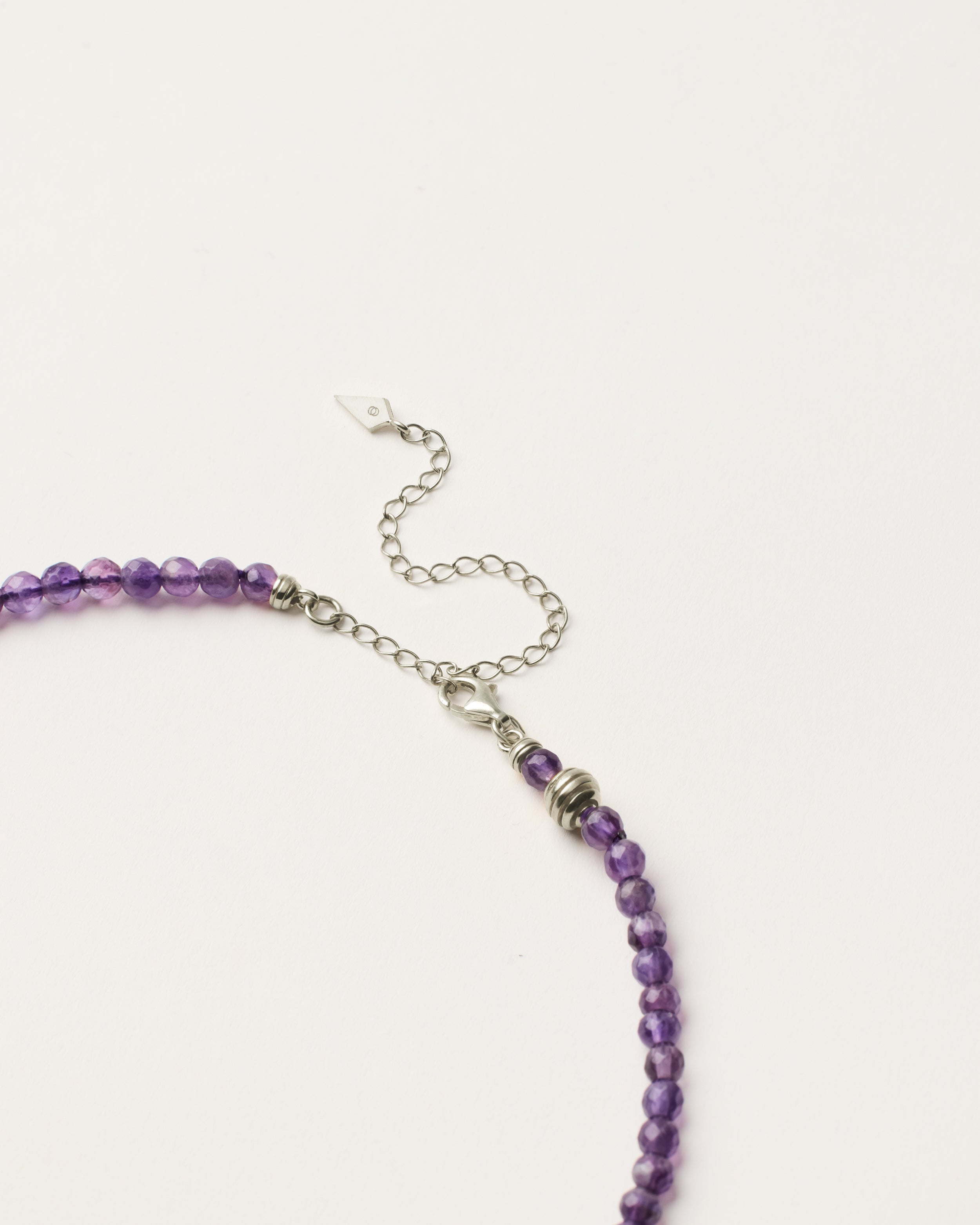 ETERNA VÉLA Amethyst necklace with polished silver spiral bead, 8 cm extension chain and clasp, arrowhead-shaped fantasy signature, and 4 mm faceted amethyst bead strand.