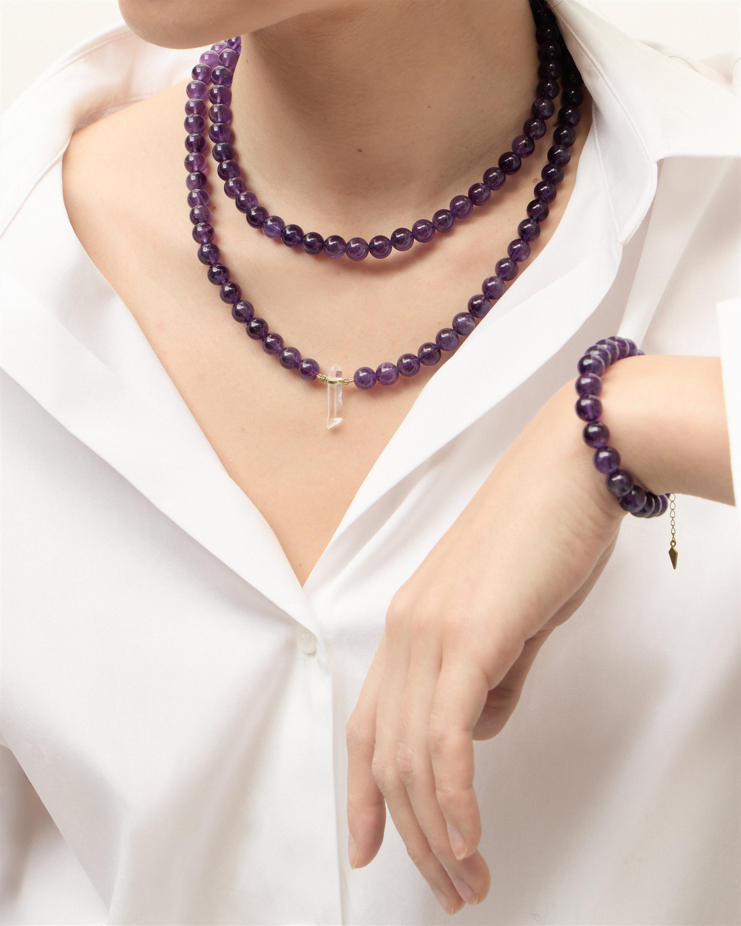 ENCARA / ETERNA VÉLA Amethyst necklaces and bracelet with polished gold spiral bead, extension chain and clasp, arrowhead-shaped fantasy signature, and 8 mm faceted amethyst bead strand and raw polished quartz point pendant.