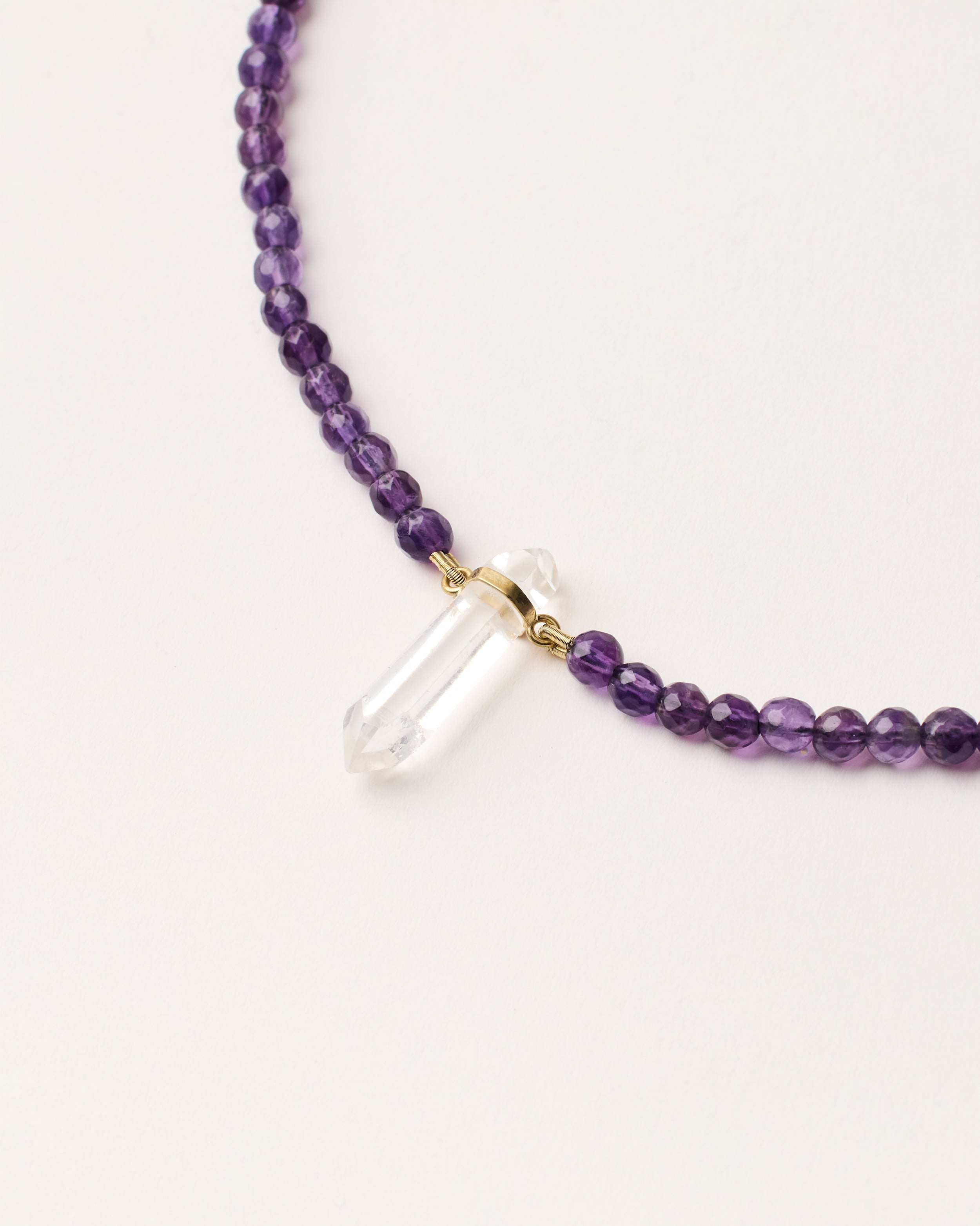 ENCARA VÉLA Amethyst necklace with raw polished quartz point pendant, gold 8 cm extension chain and clasp, arrowhead-shaped fantasy signature, and 4 mm faceted amethyst bead strand.