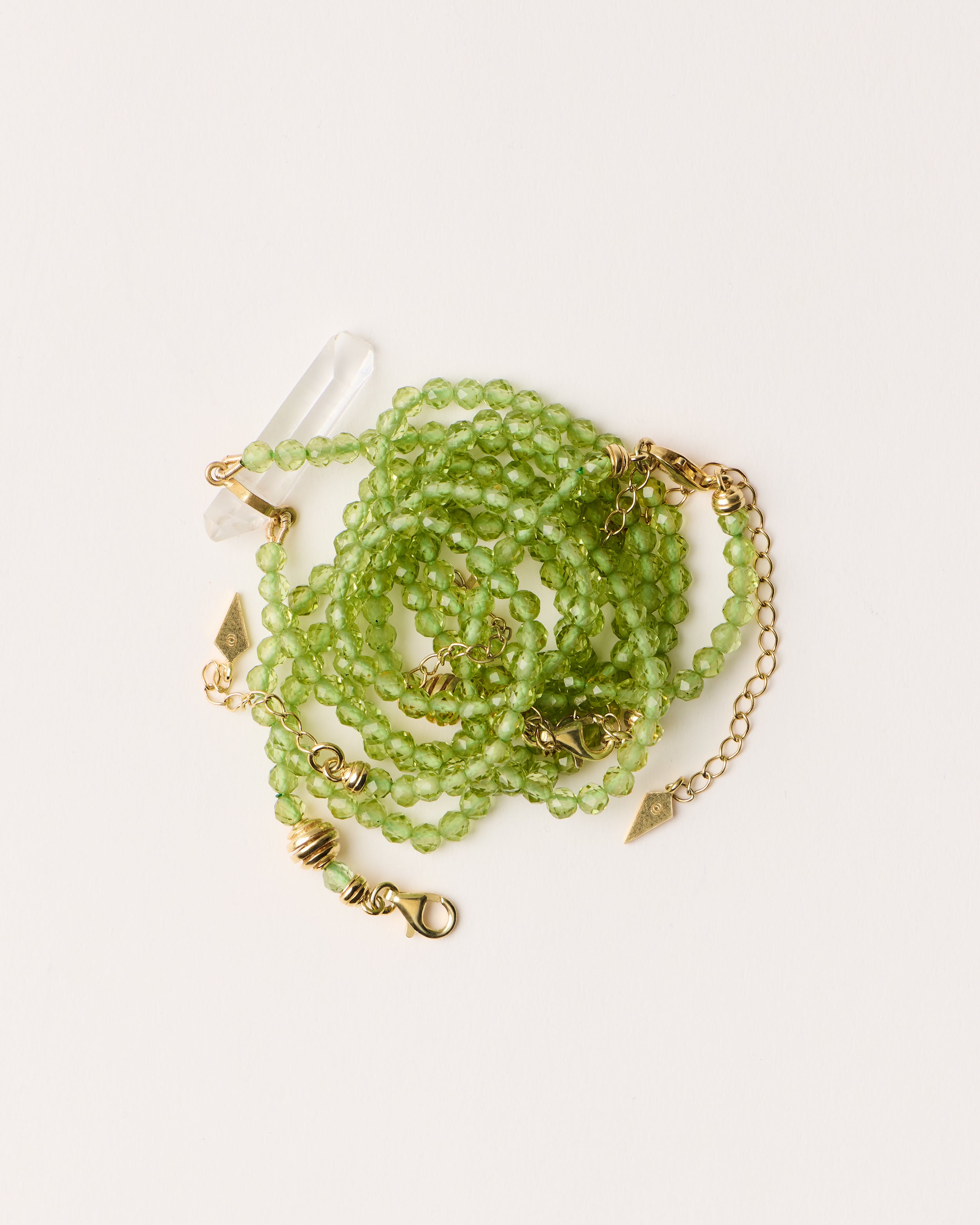 ENCARA / ETERNA OLMAR Peridot necklaces and bracelet with polished gold spiral bead, extension chain and clasp, arrowhead-shaped fantasy signature, and 4 mm faceted chrysolite bead strand and raw polished quartz point pendant.