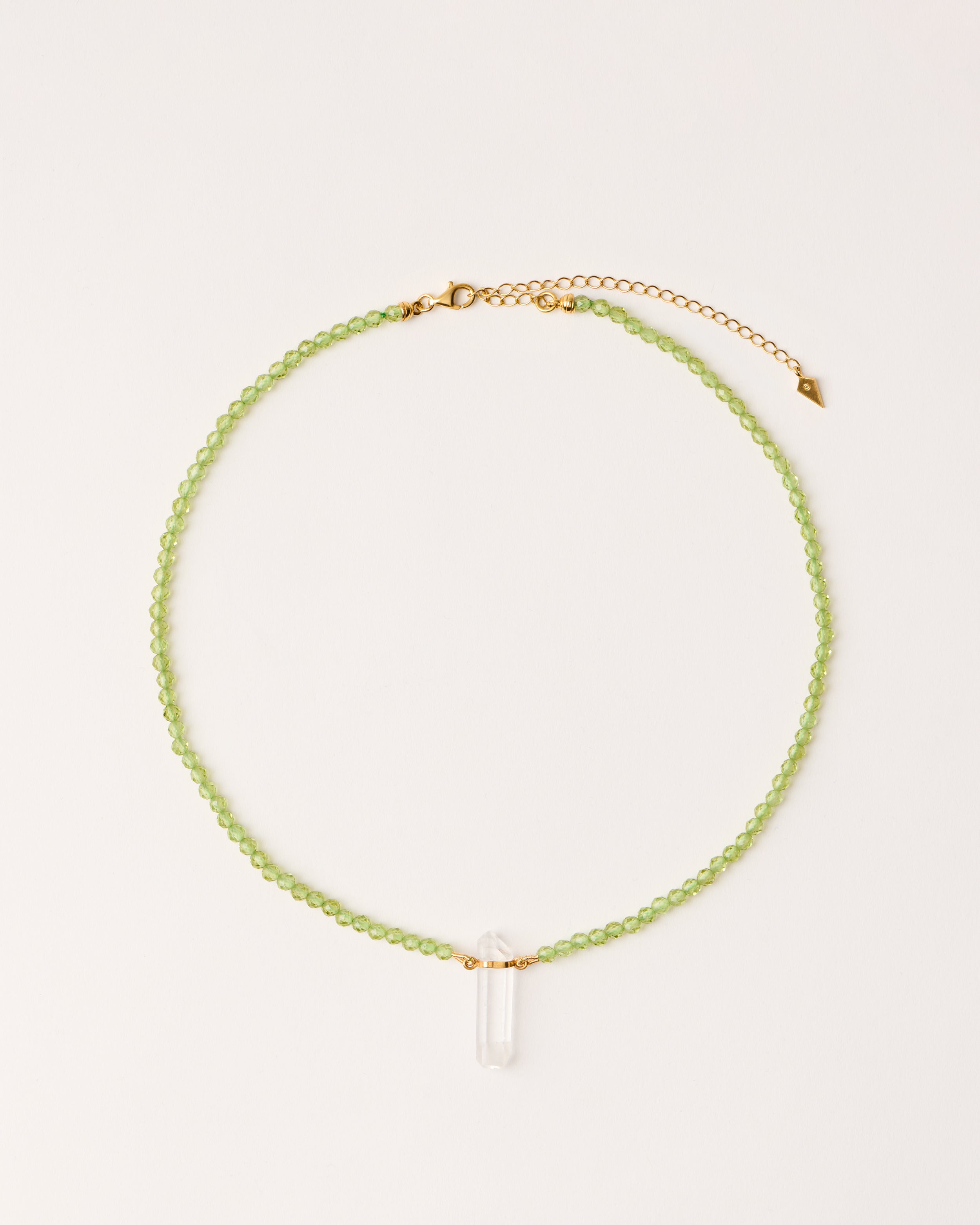 ENCARA OLMAR Peridot necklace with raw polished quartz point pendant, gold-plated silver 8 cm extension chain and clasp, arrowhead-shaped fantasy signature, and 4 mm faceted chrysolite bead strand.