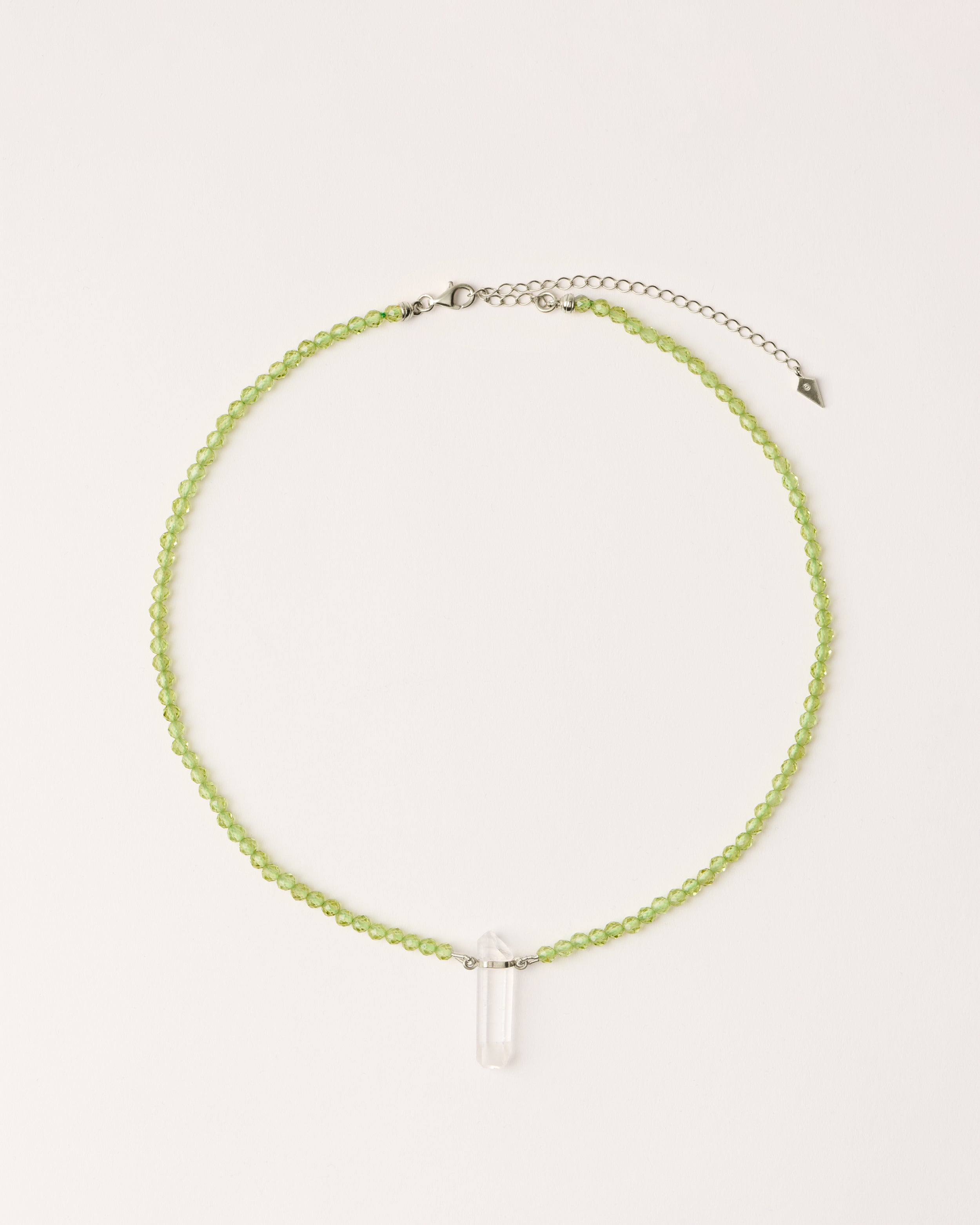 ENCARA OLMAR Peridot necklace with raw polished quartz point pendant, silver 8 cm extension chain and clasp, arrowhead-shaped fantasy signature, and 4 mm faceted chrysolite bead strand.