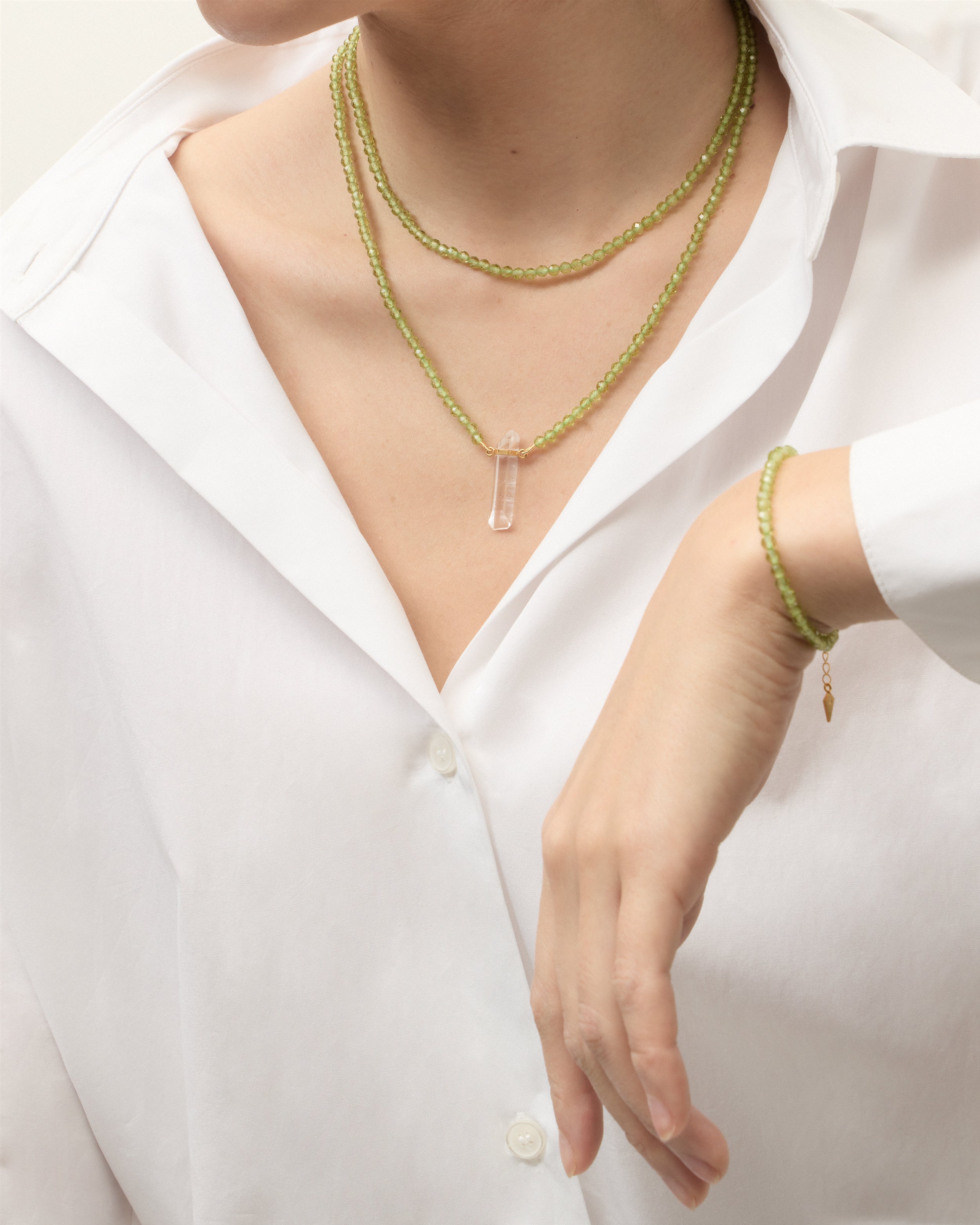 ENCARA / ETERNA OLMAR Peridot necklaces and bracelet with polished gold-plated silver spiral bead, extension chain and clasp, arrowhead-shaped fantasy signature, and 4 mm faceted chrysolite bead strand and raw polished quartz point pendant.