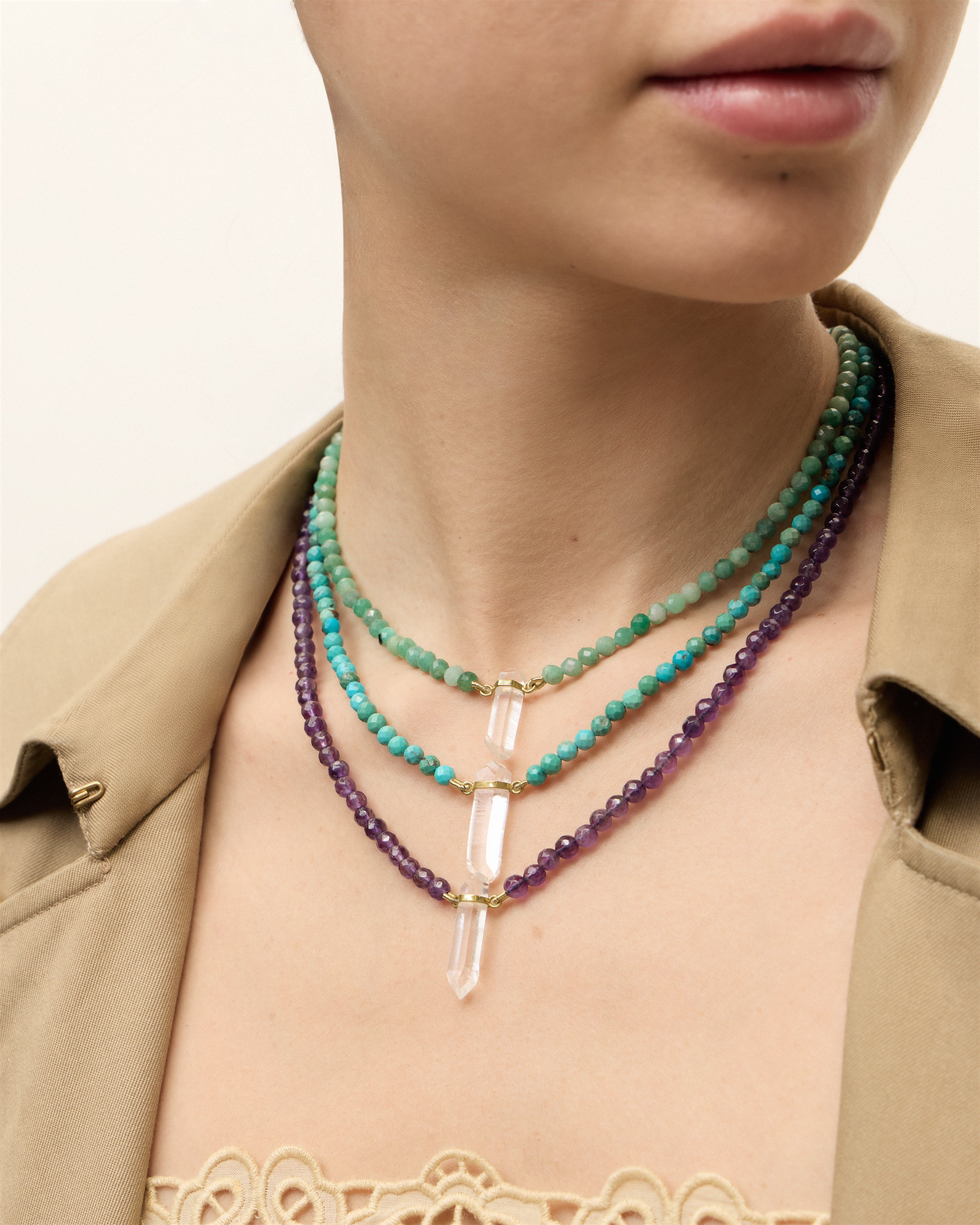 ENCARA VIRID Emerald / ENCARA AZURA Turquoise / ENCARA VÉLA Amethyst necklace with raw polished quartz point pendant, gold 8 cm extension chain and clasp, arrowhead-shaped fantasy signature, and 4 mm faceted turquoise bead strand.