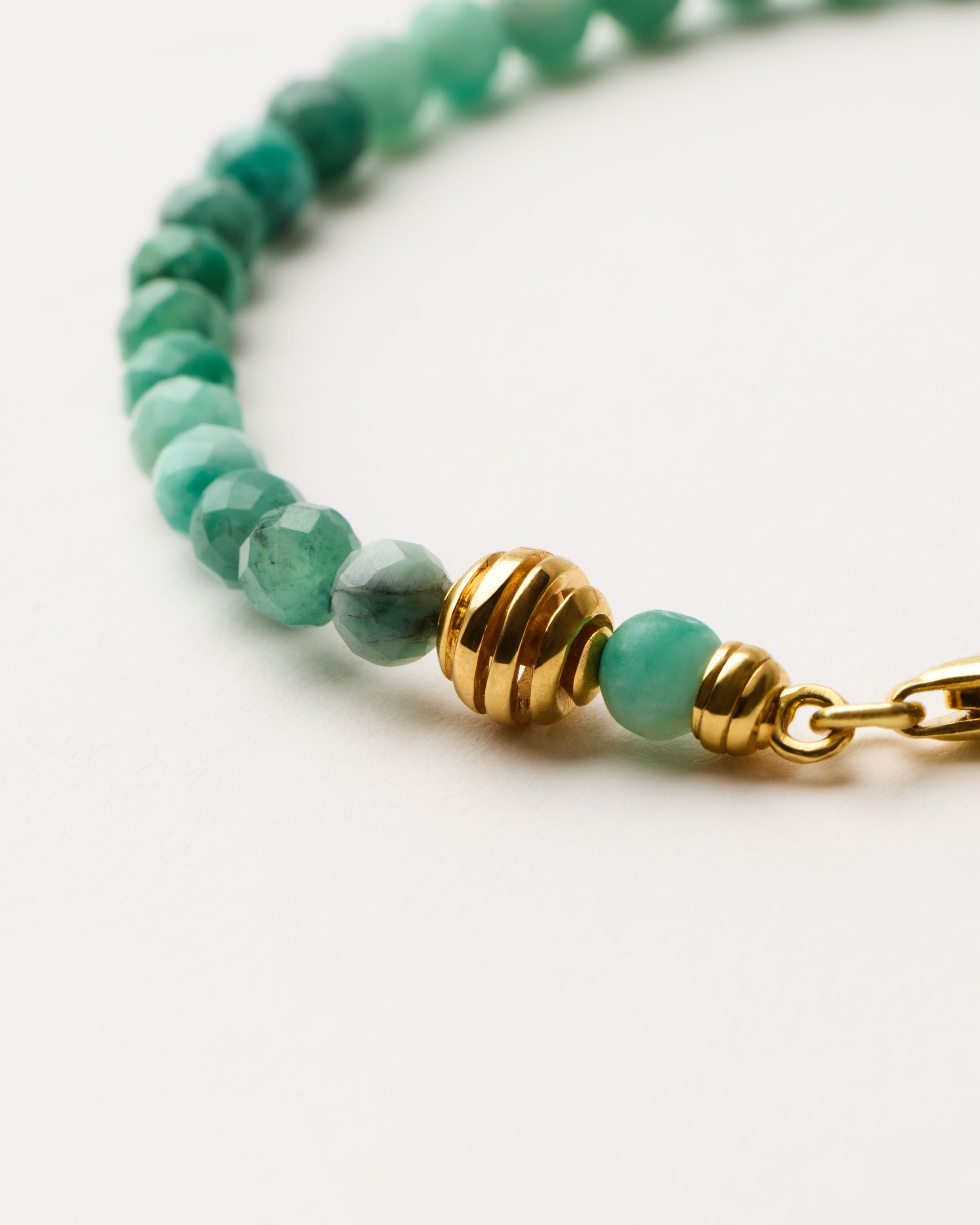 ETERNA VIRID Emerald bracelet with polished gold-plated silver spiral bead, 4 cm extension chain and clasp, arrowhead-shaped fantasy signature, and 4 mm faceted emerald bead strand.