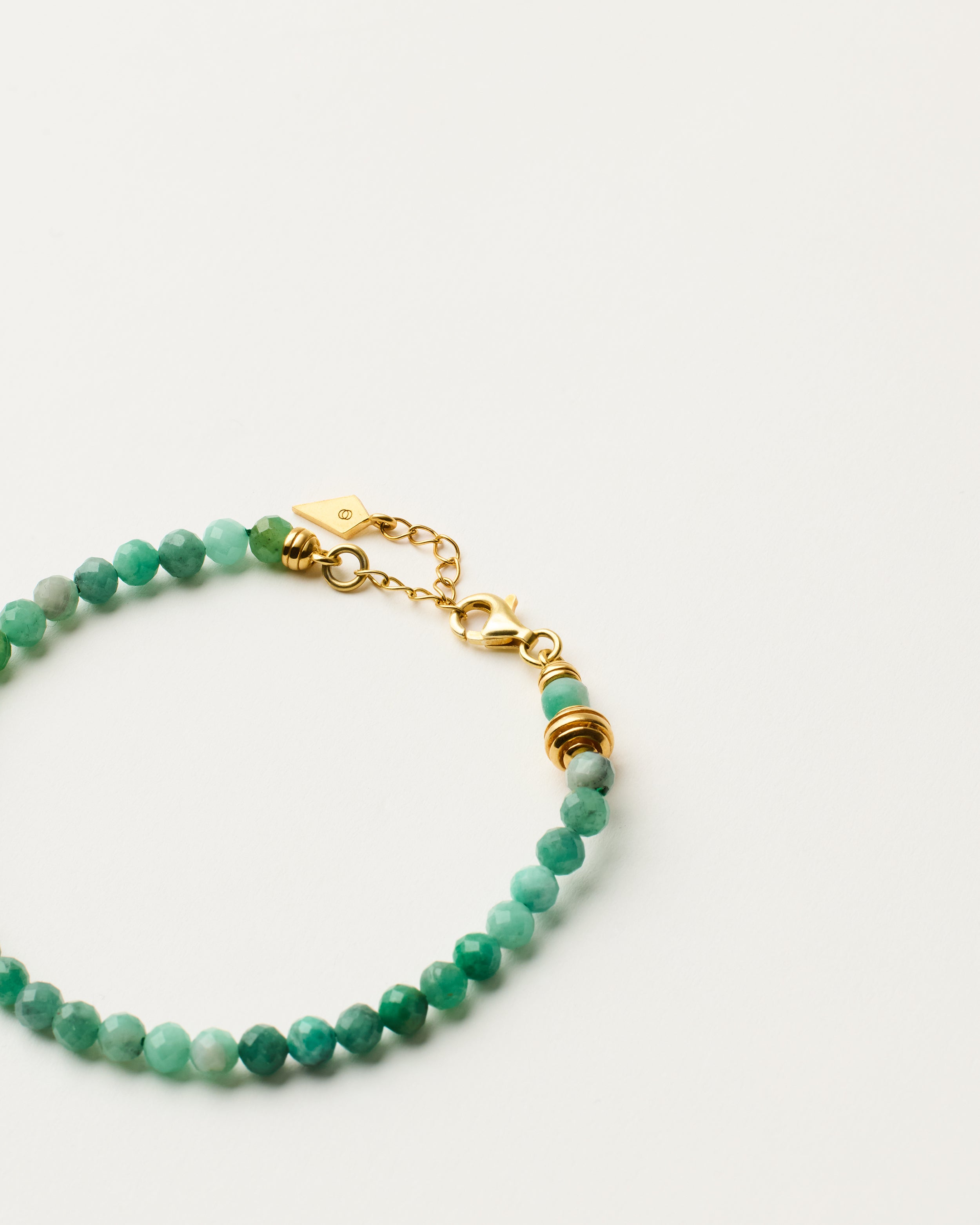 ETERNA VIRID Emerald bracelet with polished gold-plated silver spiral bead, 4 cm extension chain and clasp, arrowhead-shaped fantasy signature, and 4 mm faceted emerald bead strand.
