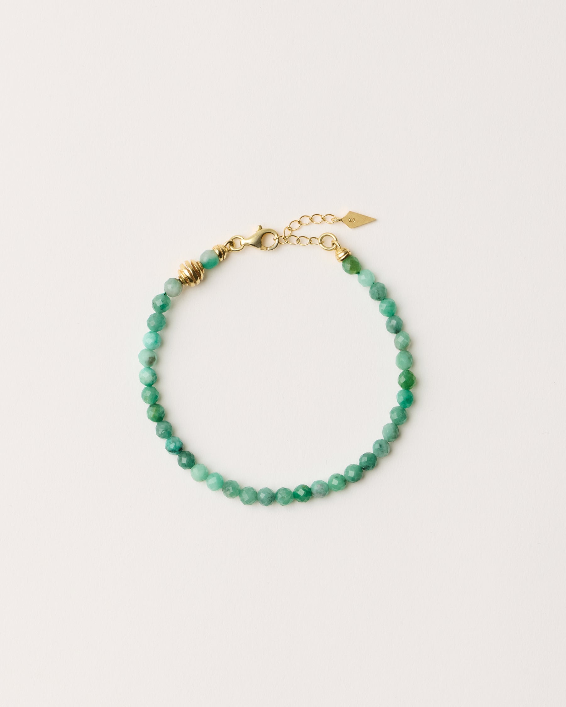 ETERNA VIRID Emerald bracelet with polished gold spiral bead, 4 cm extension chain and clasp, arrowhead-shaped fantasy signature, and 4 mm faceted emerald bead strand.